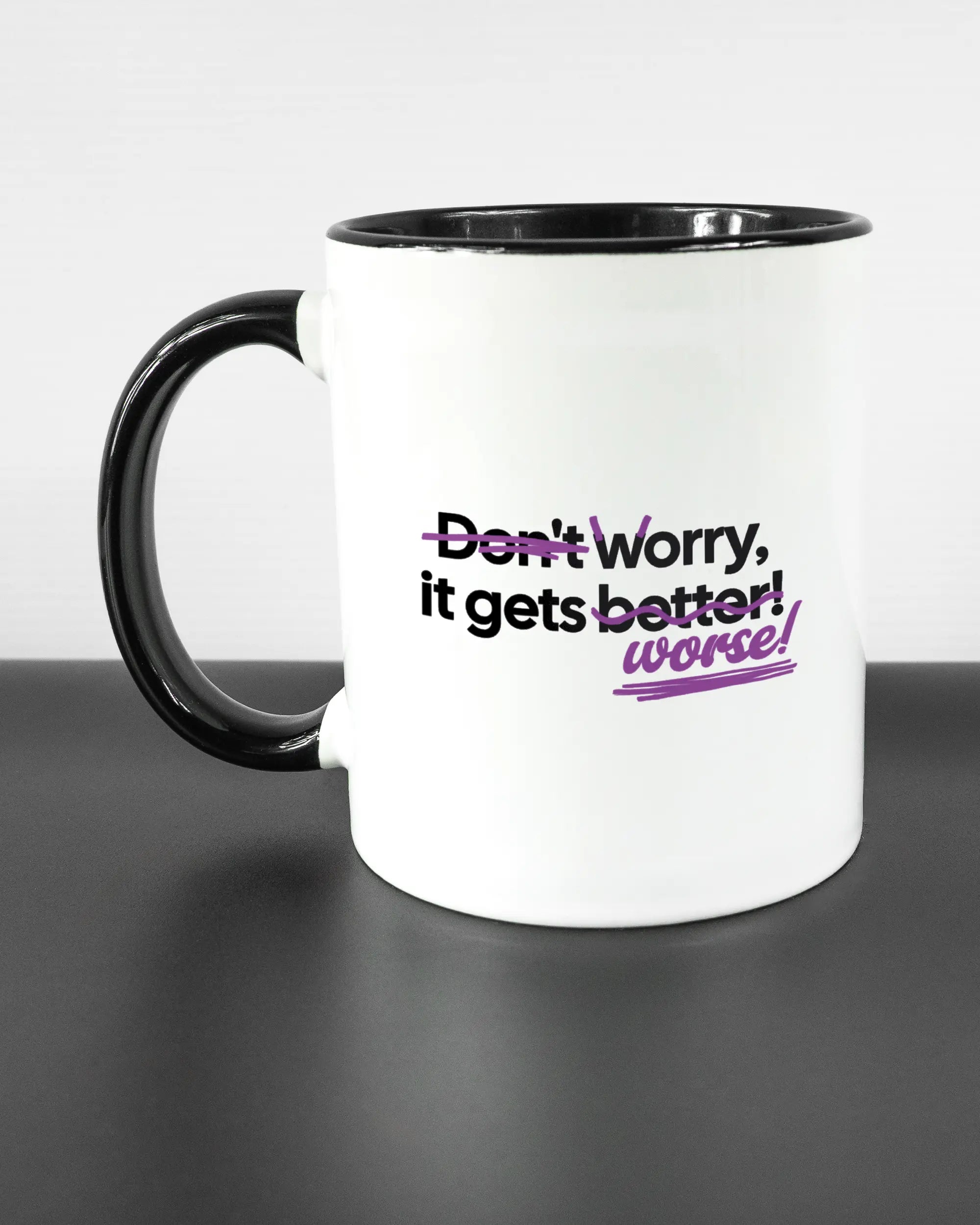 Titelbild, das die linke Seite der beidseitig bedruckten Keramiktasse von Maondo mit dem Design Worry Worse in der Farbe Duotone auf einem Holztisch zeigt