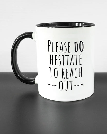 Titelbild, das die linke Seite der beidseitig bedruckten Keramiktasse von Maondo mit dem Design Please Hesitate in der Farbe Duotone auf einem Holztisch zeigt