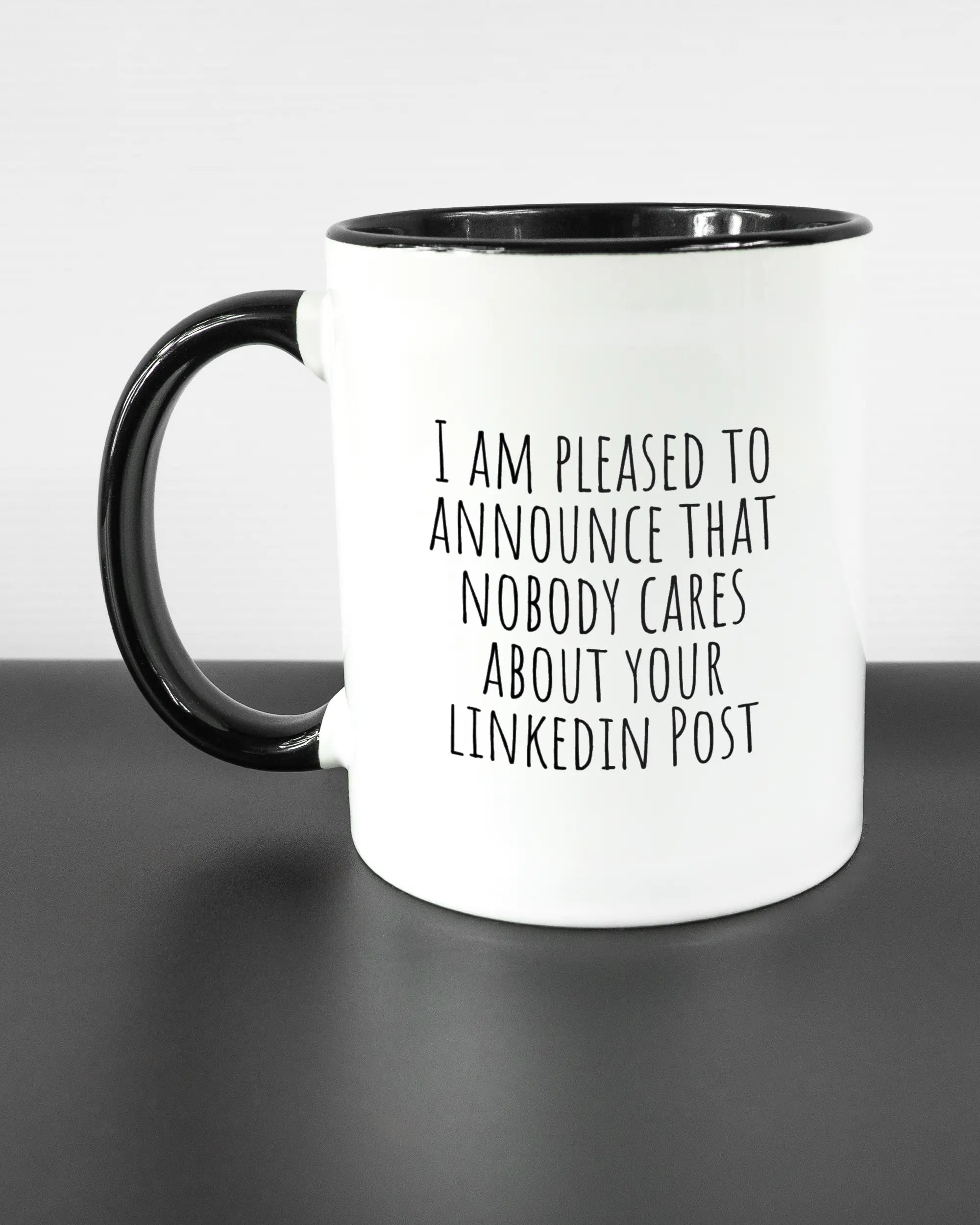 Titelbild, das die linke Seite der beidseitig bedruckten Keramiktasse von Maondo mit dem Design Please Unannounce in der Farbe Duotone auf einem Holztisch zeigt