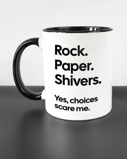 Titelbild, das die linke Seite der beidseitig bedruckten Keramiktasse von Maondo mit dem Design Rock Paper Shivers in der Farbe Duotone auf einem Holztisch zeigt