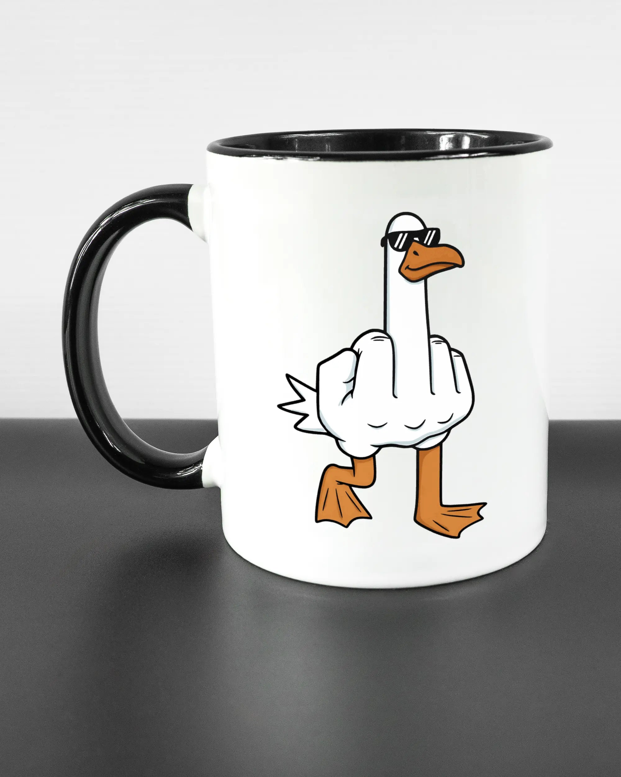 Titelbild, das die linke Seite der beidseitig bedruckten Keramiktasse von Maondo mit dem Design I give a duck in der Farbe Duotone auf einem Holztisch zeigt