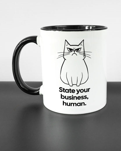 Titelbild, das die linke Seite der beidseitig bedruckten Keramiktasse von Maondo mit dem Design Grumpy Purr in der Farbe Duotone auf einem Holztisch zeigt