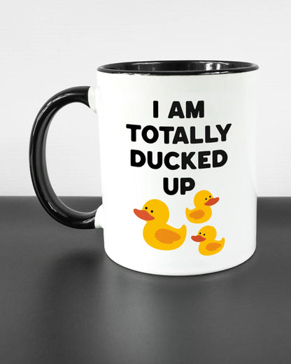 Titelbild, das die linke Seite der beidseitig bedruckten Keramiktasse von Maondo mit dem Design Ducked Up in der Farbe Duotone auf einem Holztisch zeigt