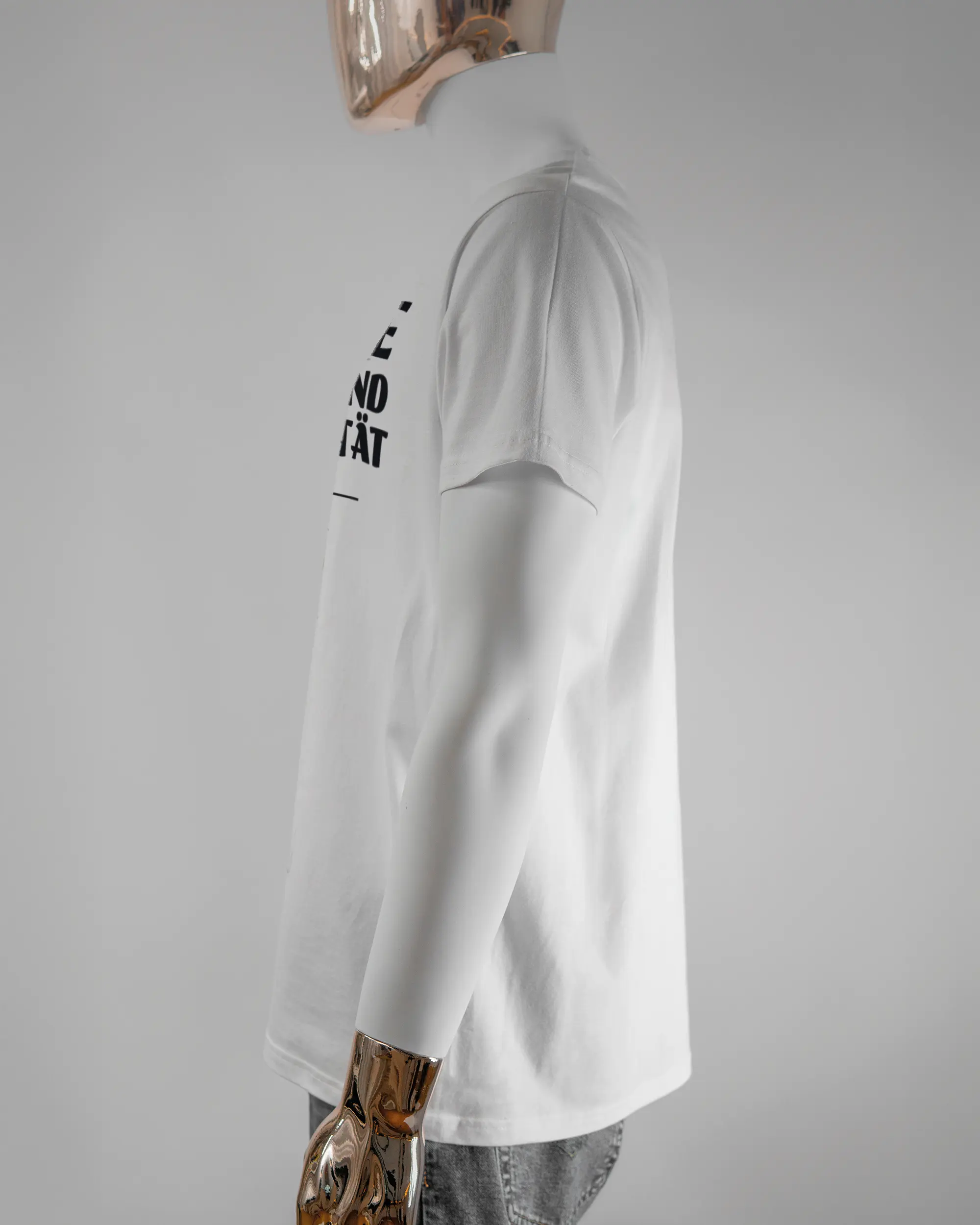 Seitenansicht des Basic Unisex T-Shirt Soft von Maondo mit dem Design Keine Eile vorne in der Farbe White und in der Größe L getragen von einer maskulinen Puppe