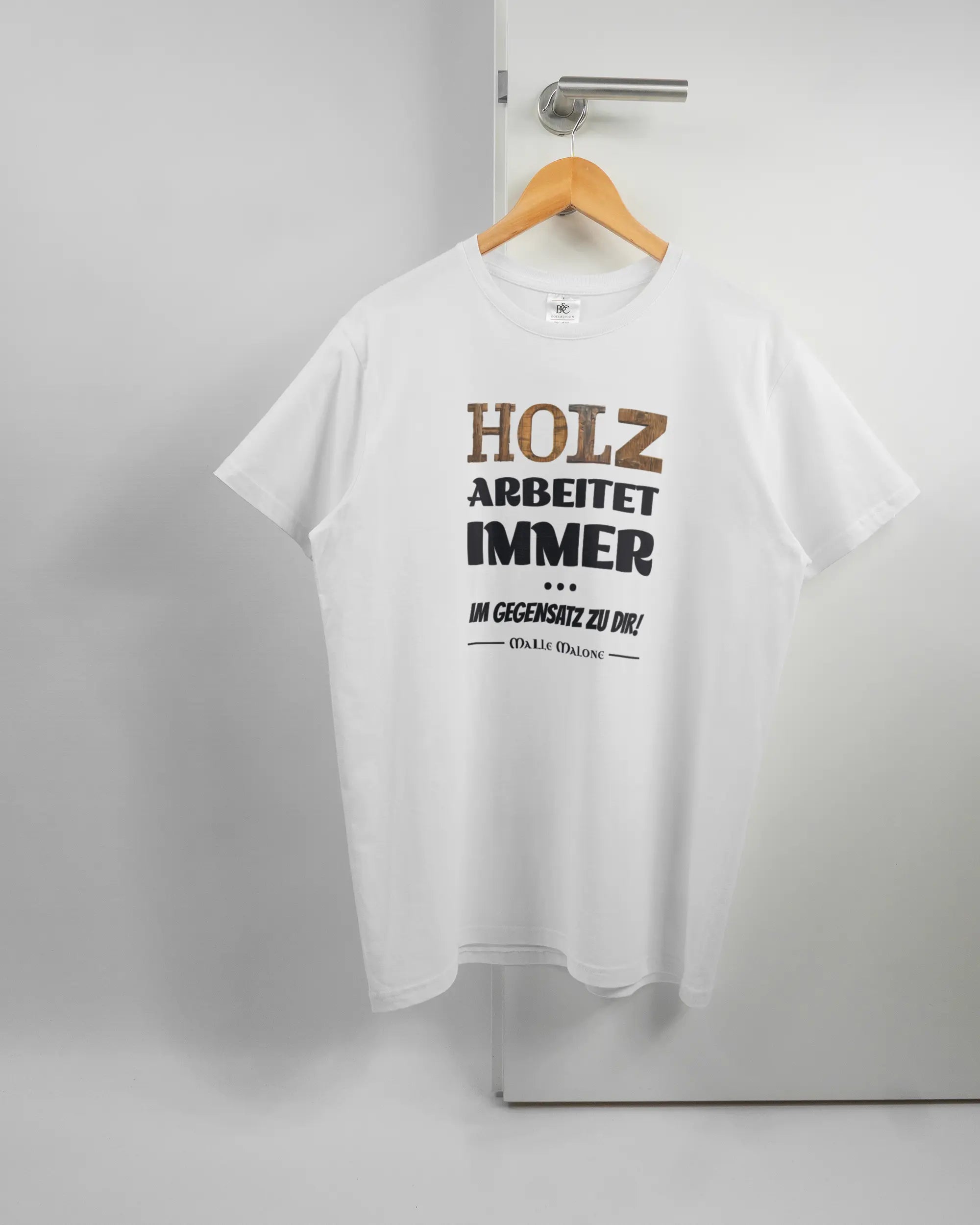Vorderseite des Basic Unisex T-Shirt Soft von Maondo mit dem Design Holzarbeit in der Farbe White und in der Größe L auf einem Bügel an der Türklinke aufgehängt