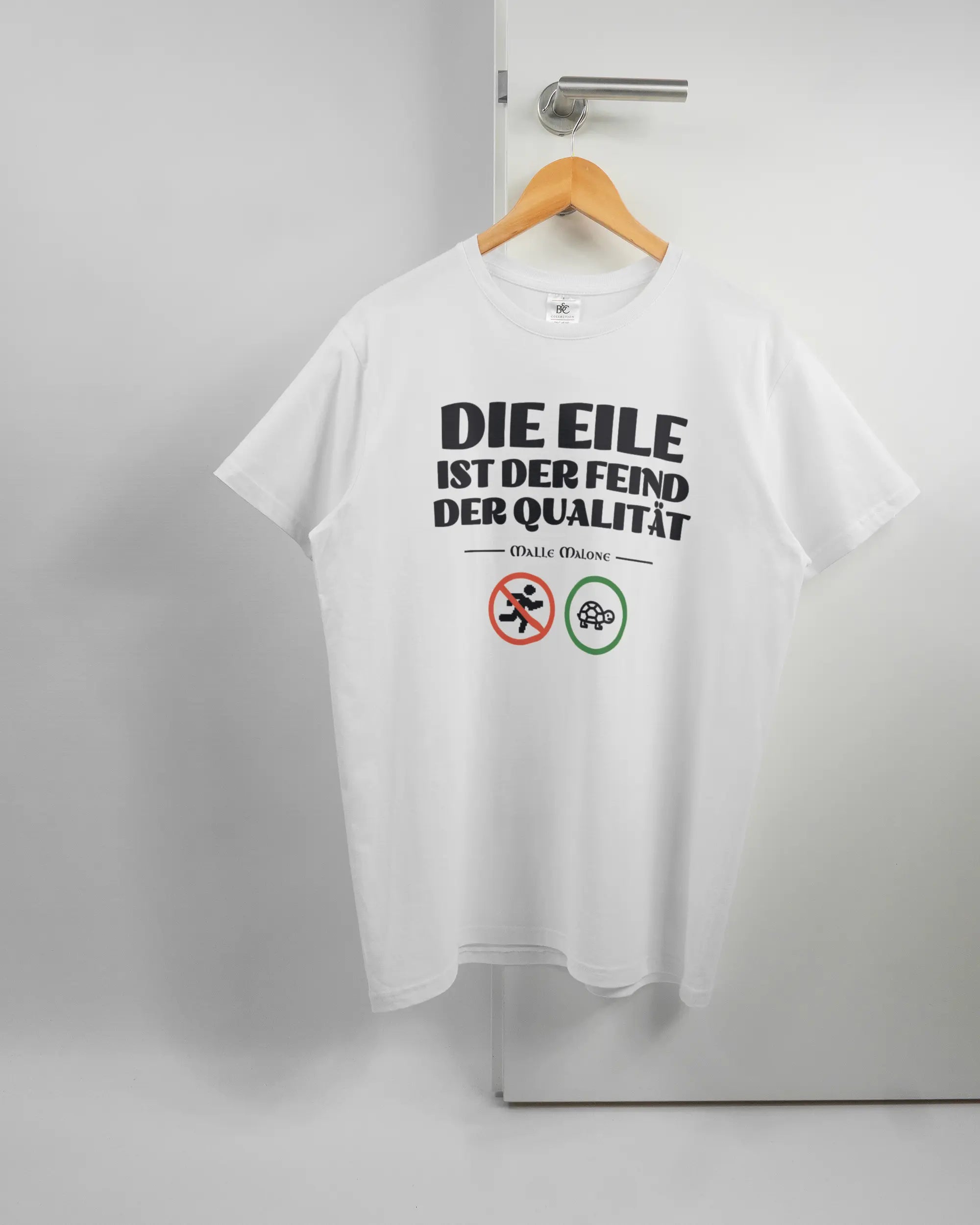 Vorderseite des Basic Unisex T-Shirt Soft von Maondo mit dem Design Keine Eile in der Farbe White und in der Größe L auf einem Bügel an der Türklinke aufgehängt