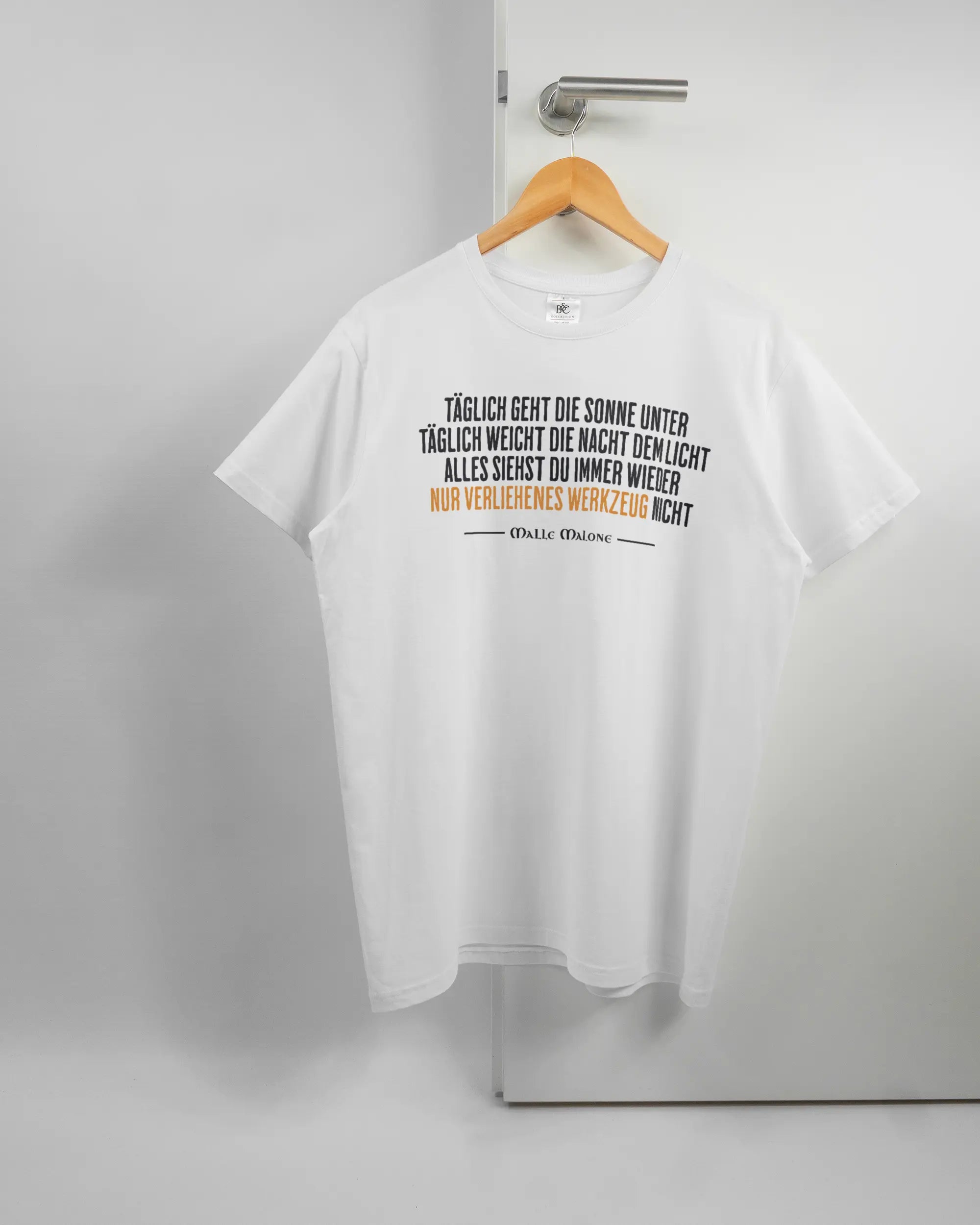 Vorderseite des Basic Unisex T-Shirt Soft von Maondo mit dem Design Wegzeug in der Farbe White und in der Größe L auf einem Bügel an der Türklinke aufgehängt