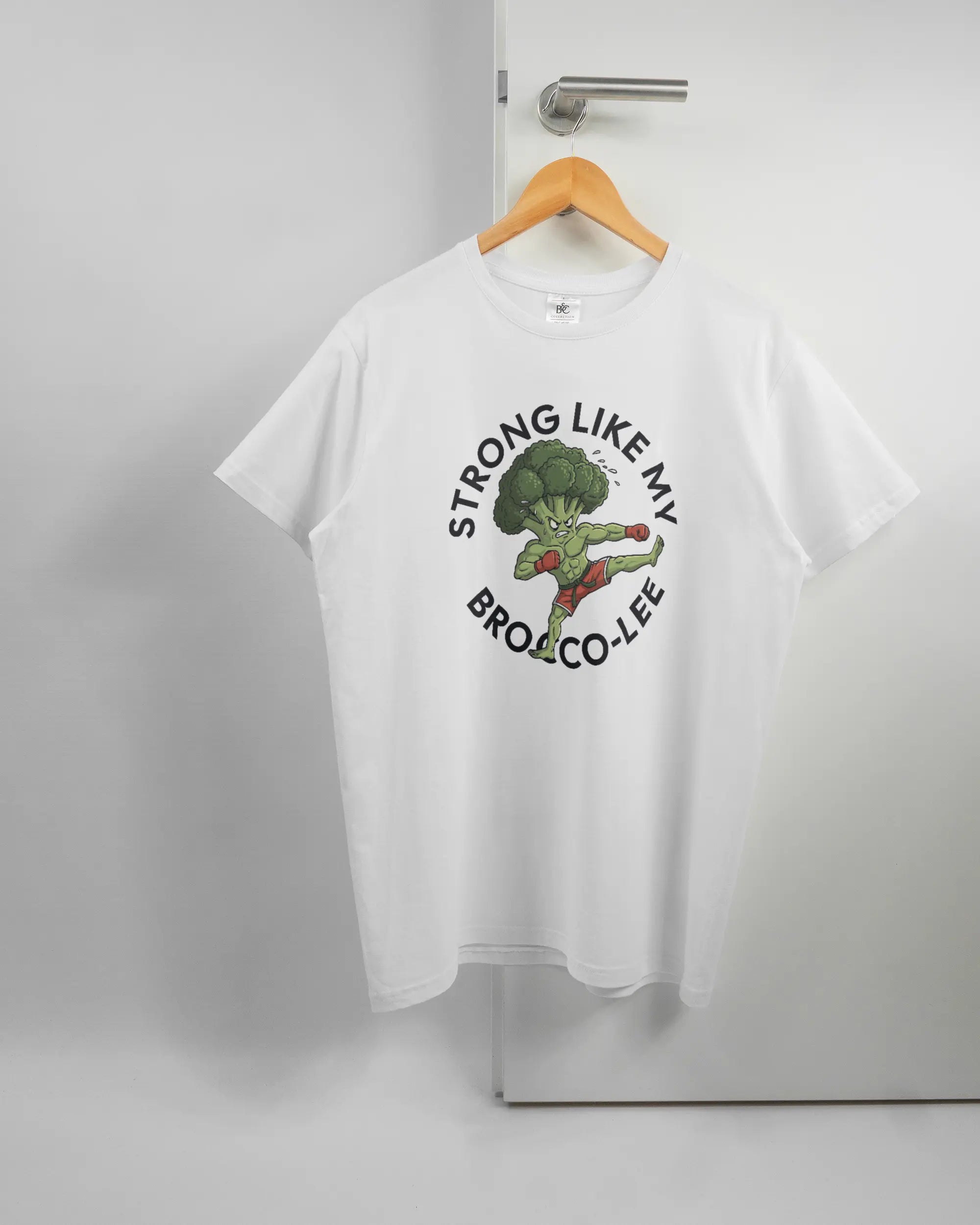 Vorderseite des Basic Unisex T-Shirt Soft von Maondo mit dem Design Brocco-Lee in der Farbe White und in der Größe L auf einem Bügel an der Türklinke aufgehängt