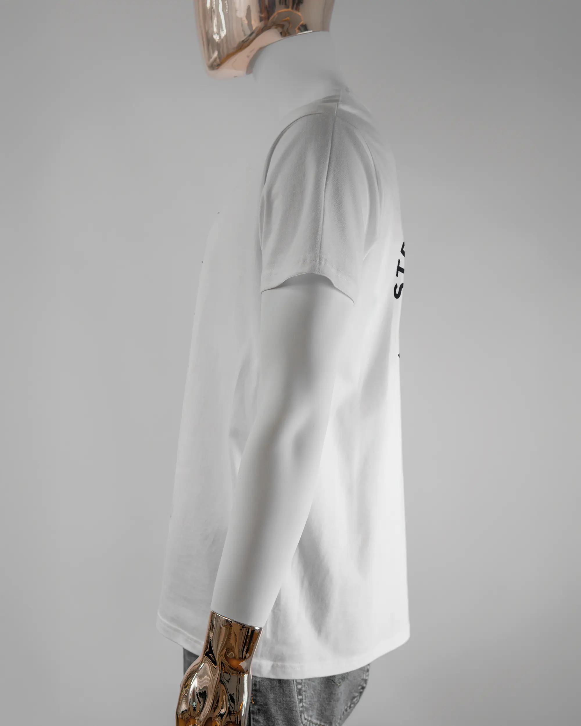 Seitenansicht des Basic Unisex T-Shirt Soft von Maondo mit dem Design Brocco-Lee hinten in der Farbe White und in der Größe L getragen von einer maskulinen Puppe