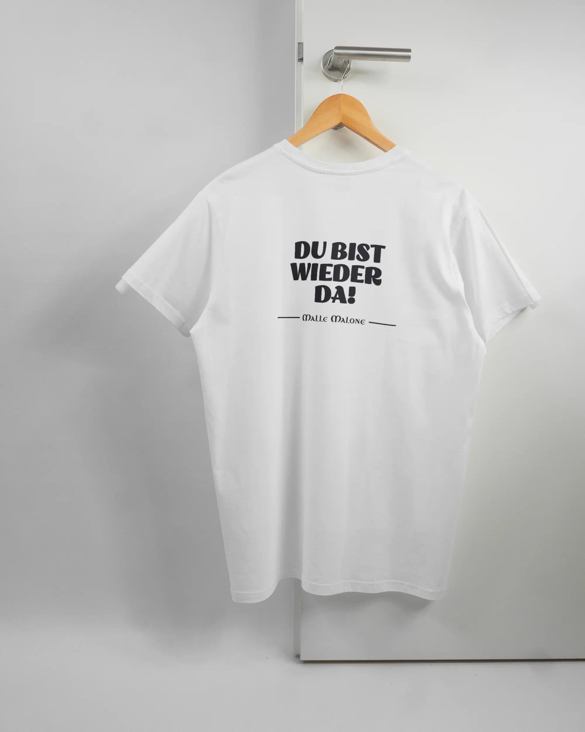 Rückseite des Basic Unisex T-Shirt Soft von Maondo mit dem Design Wieder da in der Farbe White und in der Größe L auf einem Bügel an der Türklinke aufgehängt
