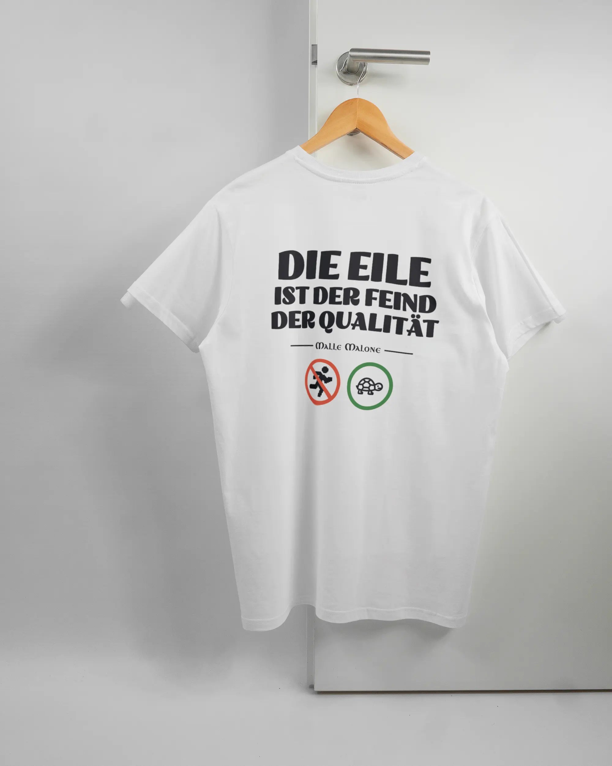 Rückseite des Basic Unisex T-Shirt Soft von Maondo mit dem Design Keine Eile in der Farbe White und in der Größe L auf einem Bügel an der Türklinke aufgehängt