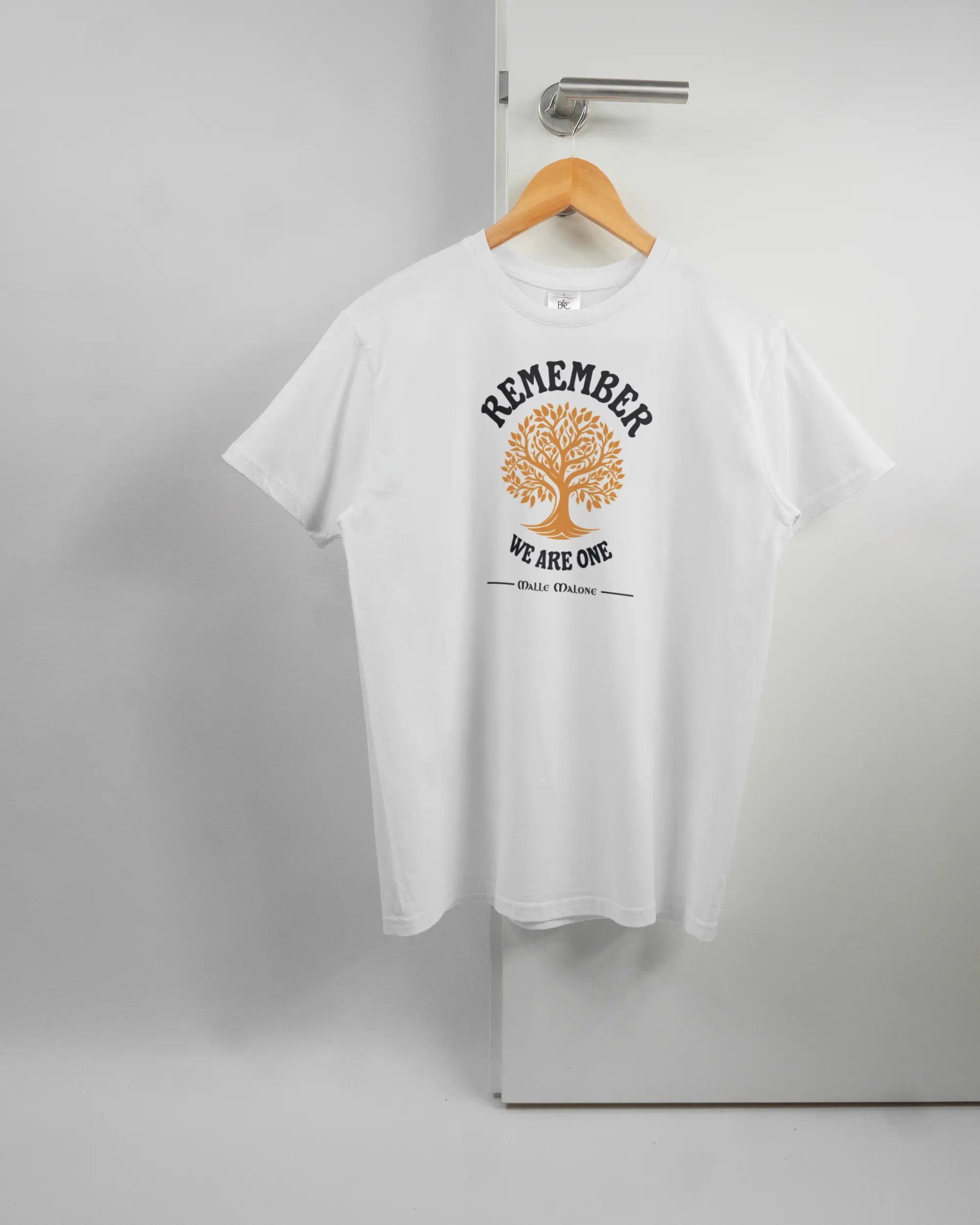 Vorderseite des Basic Unisex T-Shirt Soft von Maondo mit dem Design We are one in der Farbe White und in der Größe S auf einem Bügel an der Türklinke aufgehängt