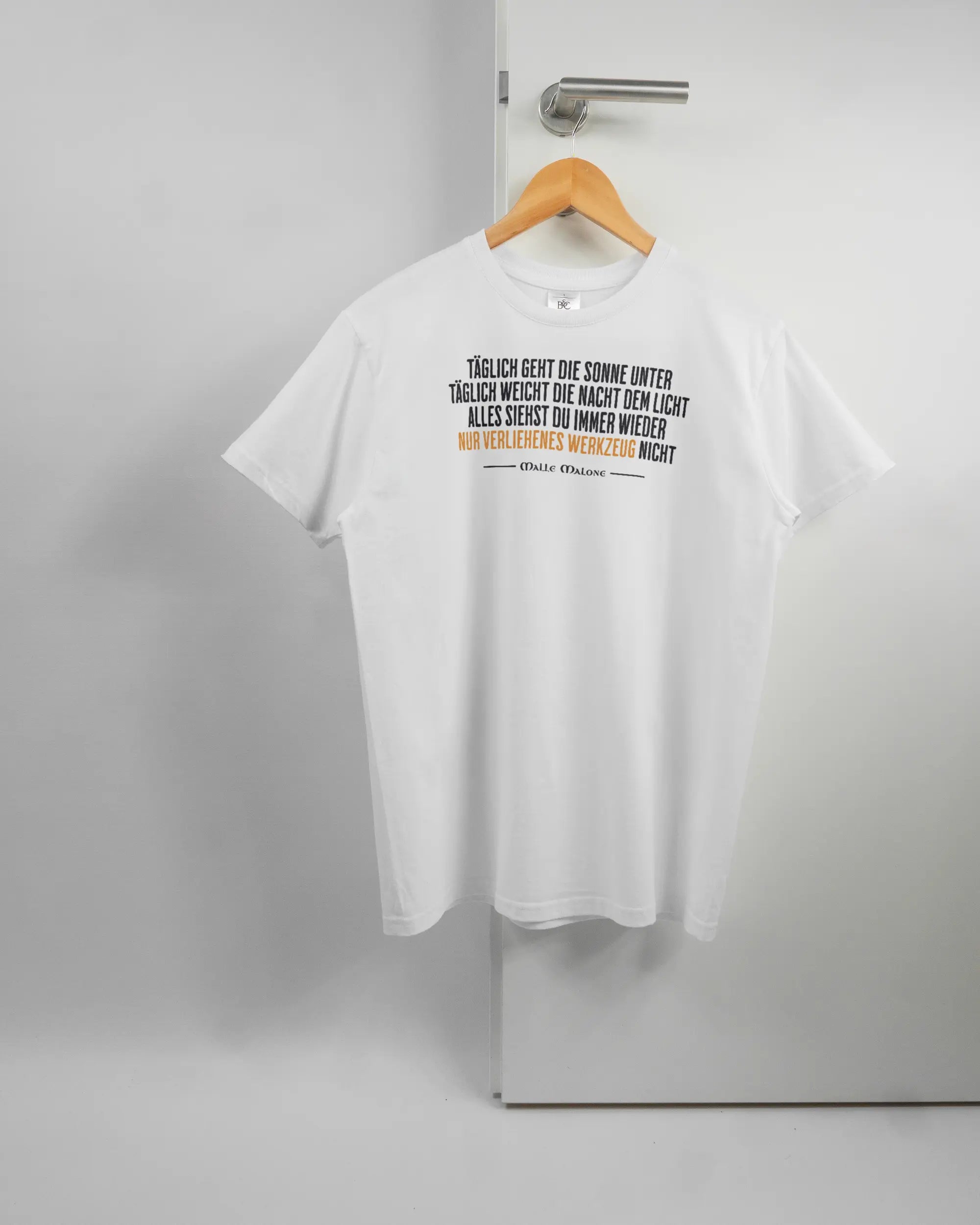 Vorderseite des Basic Unisex T-Shirt Soft von Maondo mit dem Design Wegzeug in der Farbe White und in der Größe S auf einem Bügel an der Türklinke aufgehängt