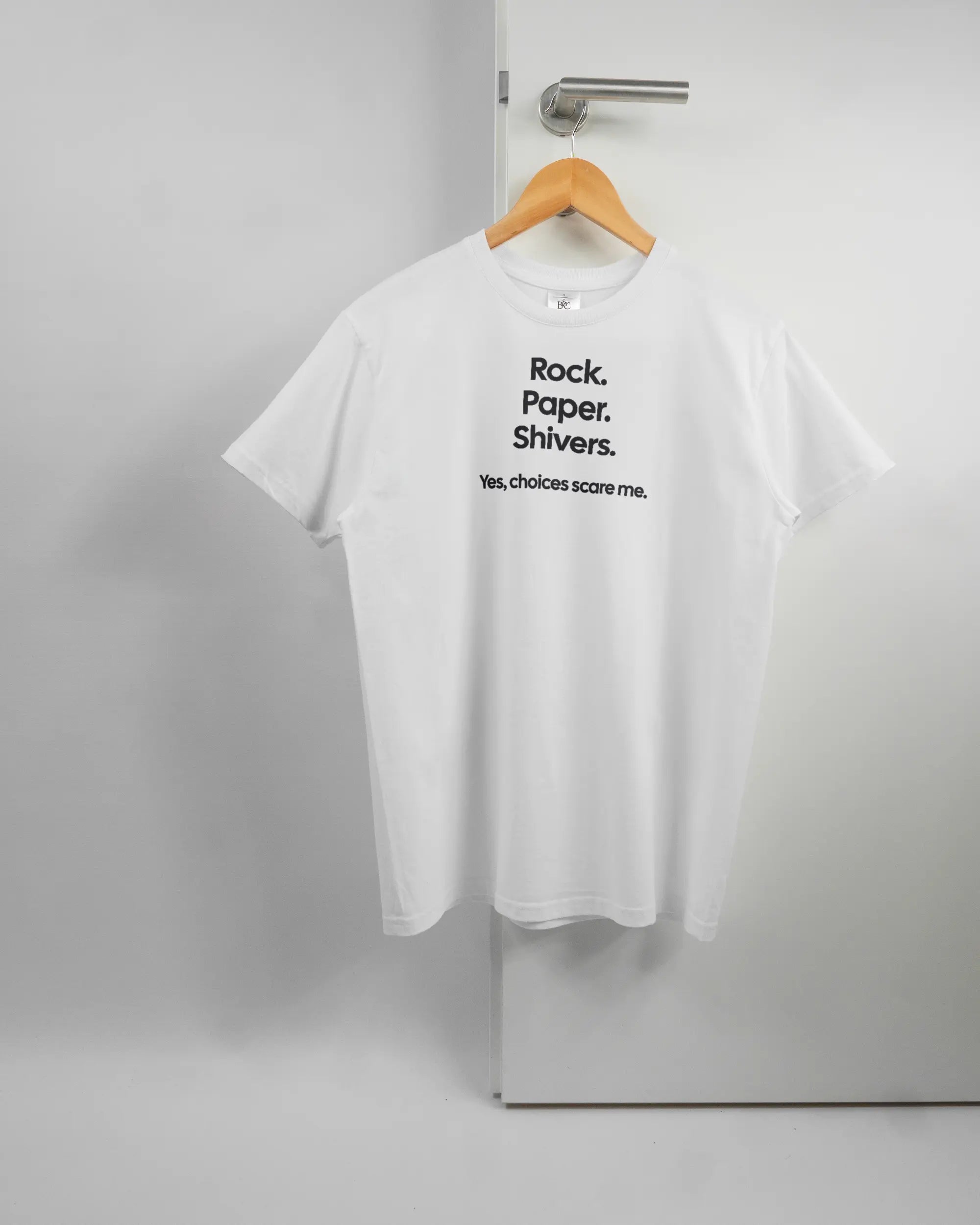 Vorderseite des Basic Unisex T-Shirt Soft von Maondo mit dem Design Rock Paper Shivers in der Farbe White und in der Größe S auf einem Bügel an der Türklinke aufgehängt