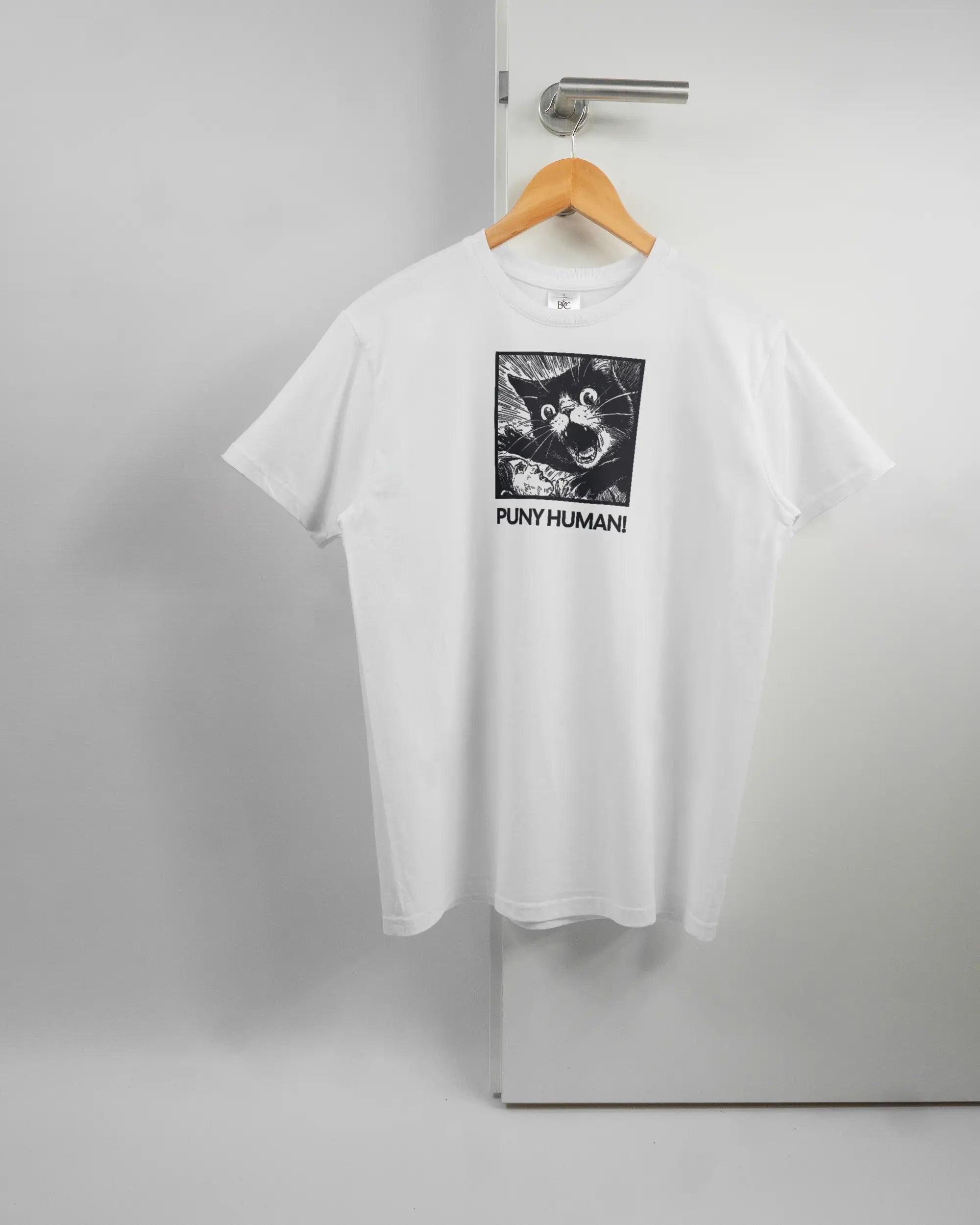Vorderseite des Basic Unisex T-Shirt Soft von Maondo mit dem Design Puny Human in der Farbe White und in der Größe S auf einem Bügel an der Türklinke aufgehängt
