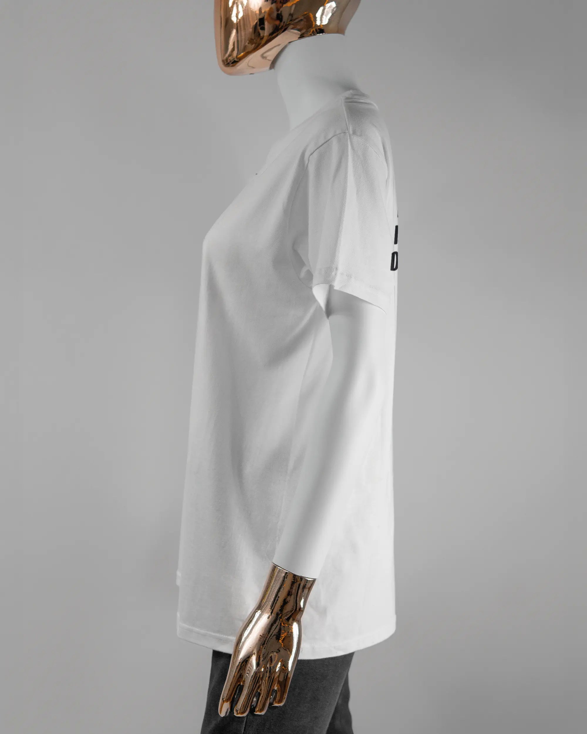 Seitenansicht des Basic Unisex T-Shirt Soft von Maondo mit dem Design Keine Eile hinten in der Farbe White und in der Größe S getragen von einer femininen Puppe