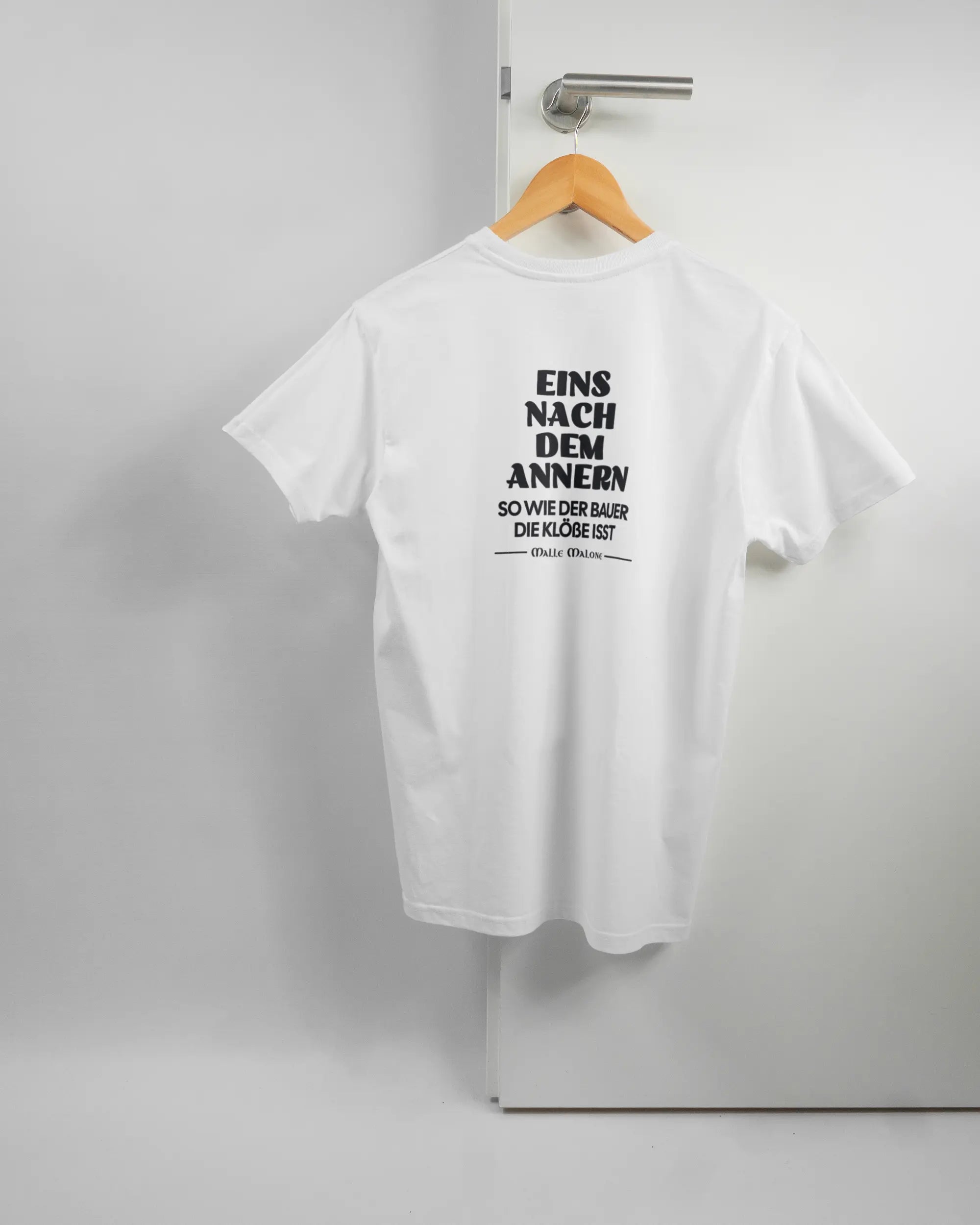 Rückseite des Basic Unisex T-Shirt Soft von Maondo mit dem Design Eins nach dem Annern in der Farbe White und in der Größe S auf einem Bügel an der Türklinke aufgehängt