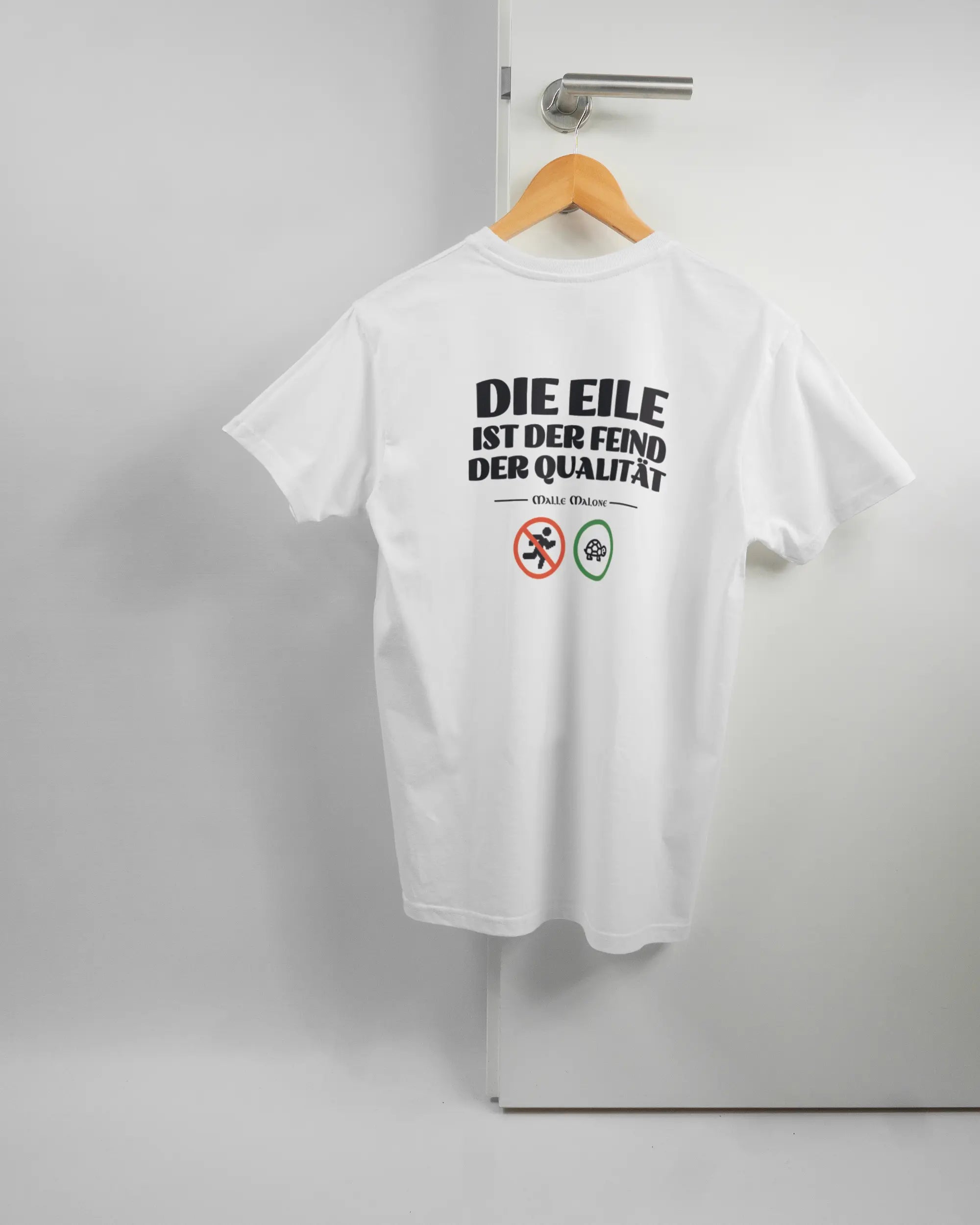 Rückseite des Basic Unisex T-Shirt Soft von Maondo mit dem Design Keine Eile in der Farbe White und in der Größe S auf einem Bügel an der Türklinke aufgehängt