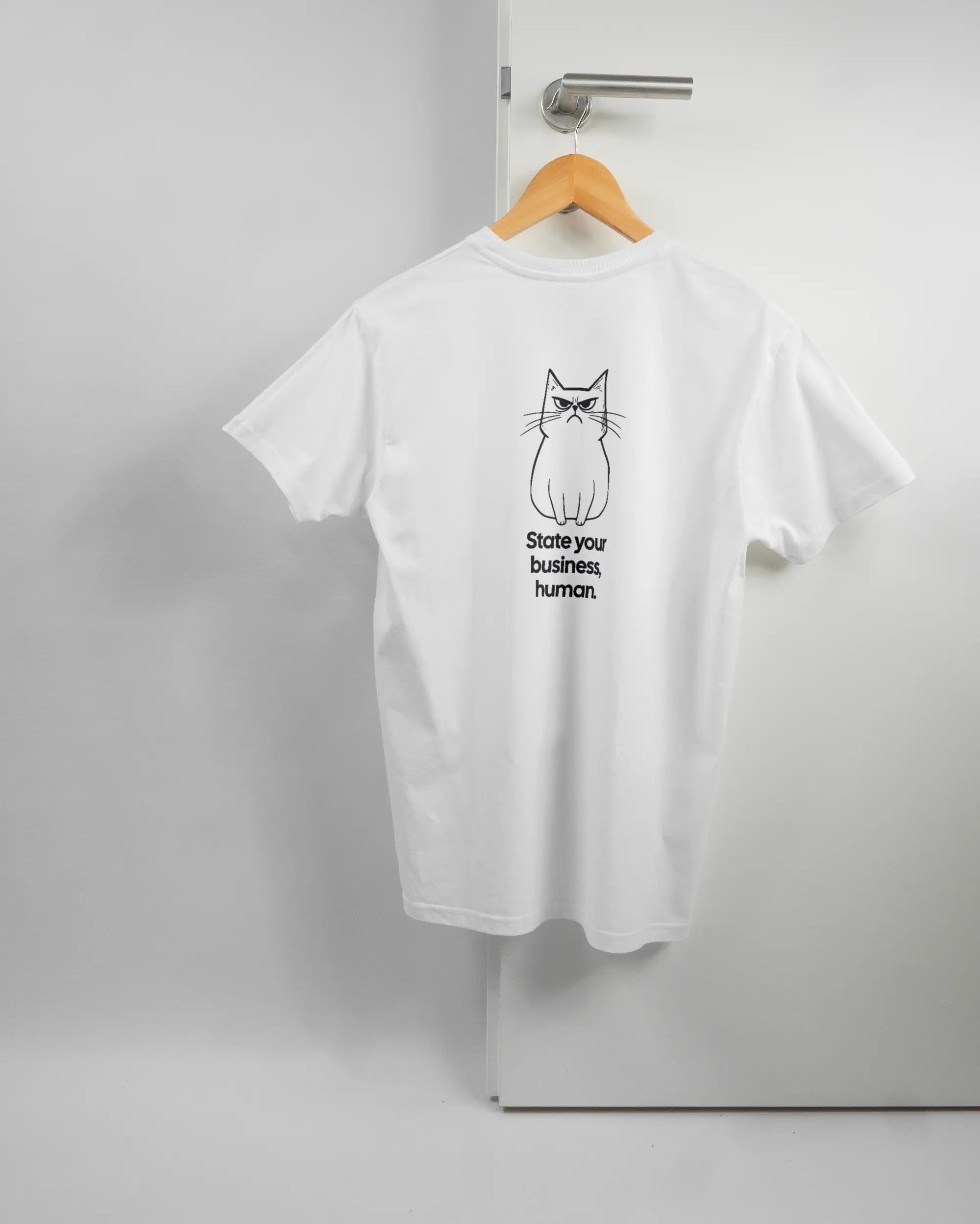 Rückseite des Basic Unisex T-Shirt Soft von Maondo mit dem Design Grumpy Purr in der Farbe White und in der Größe S auf einem Bügel an der Türklinke aufgehängt