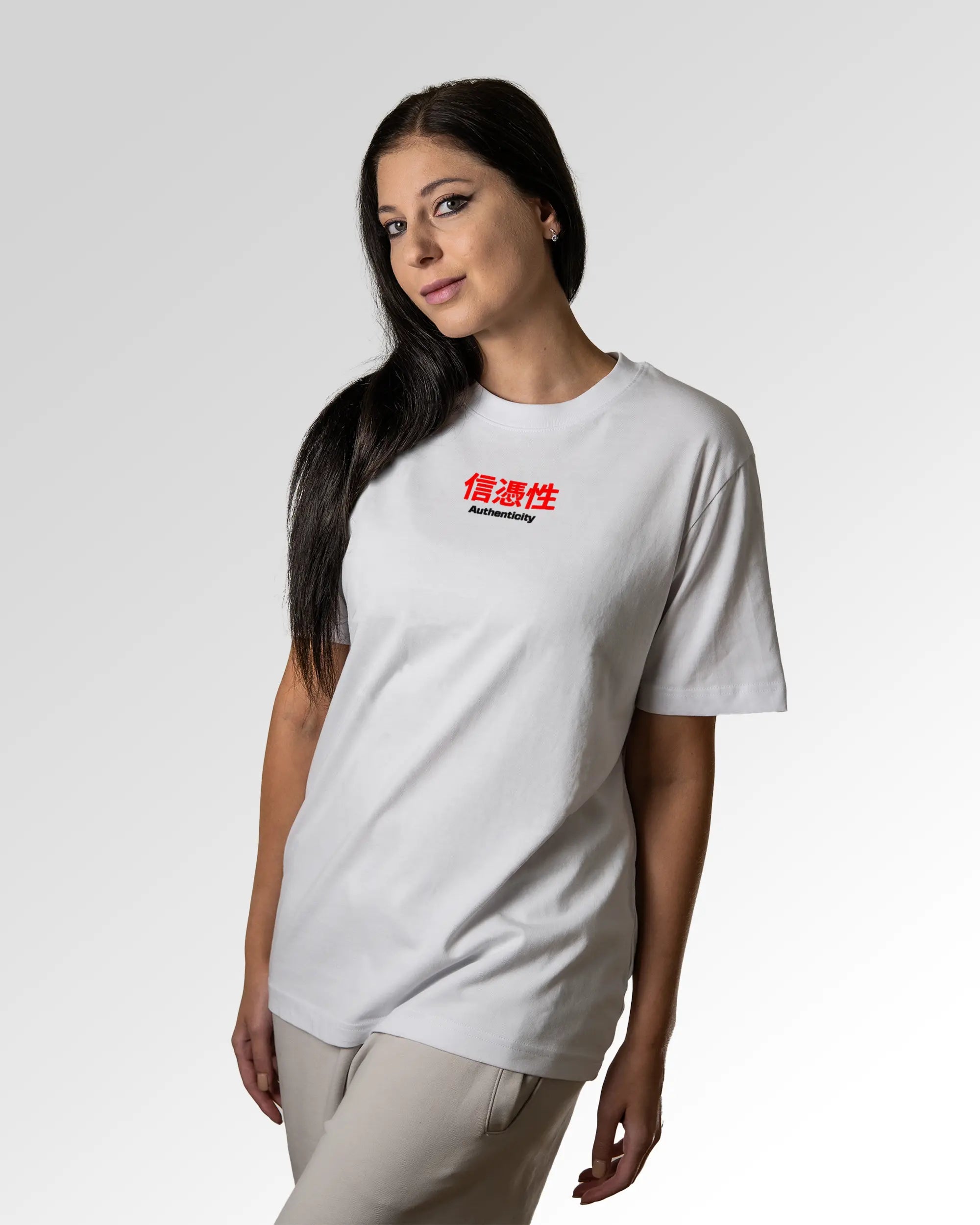 Weiblicher Modelshot der primären Druckseite des Organic Unisex T-Shirts von Maondo im Relaxed Fit mit dem Design Authentic Shit in der Farbe White