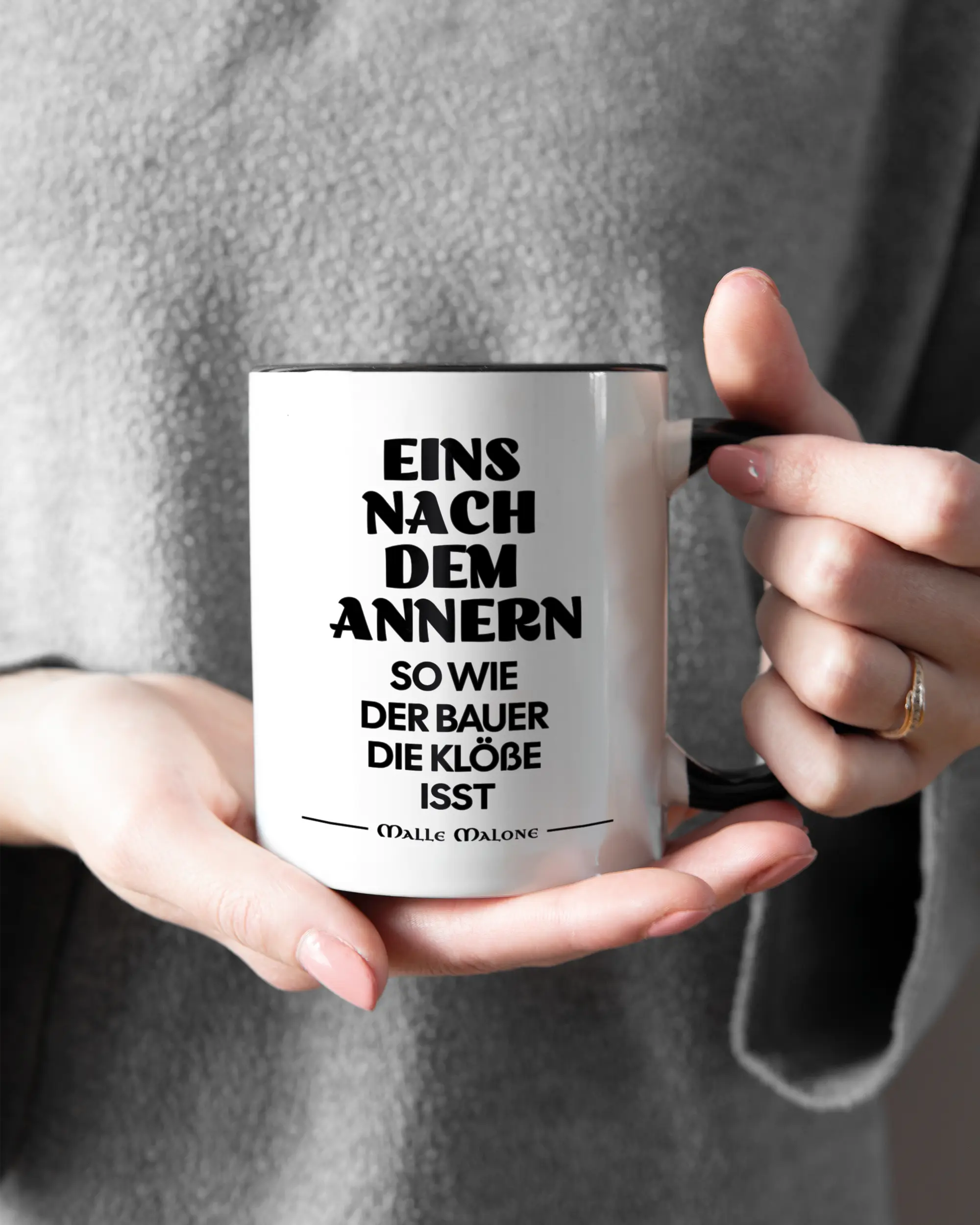 Rechte Seite der beidseitig bedruckten Keramiktasse von Maondo mit dem Design Eins nach dem Annern in der Farbe Duotone gehalten von Frauenhänden