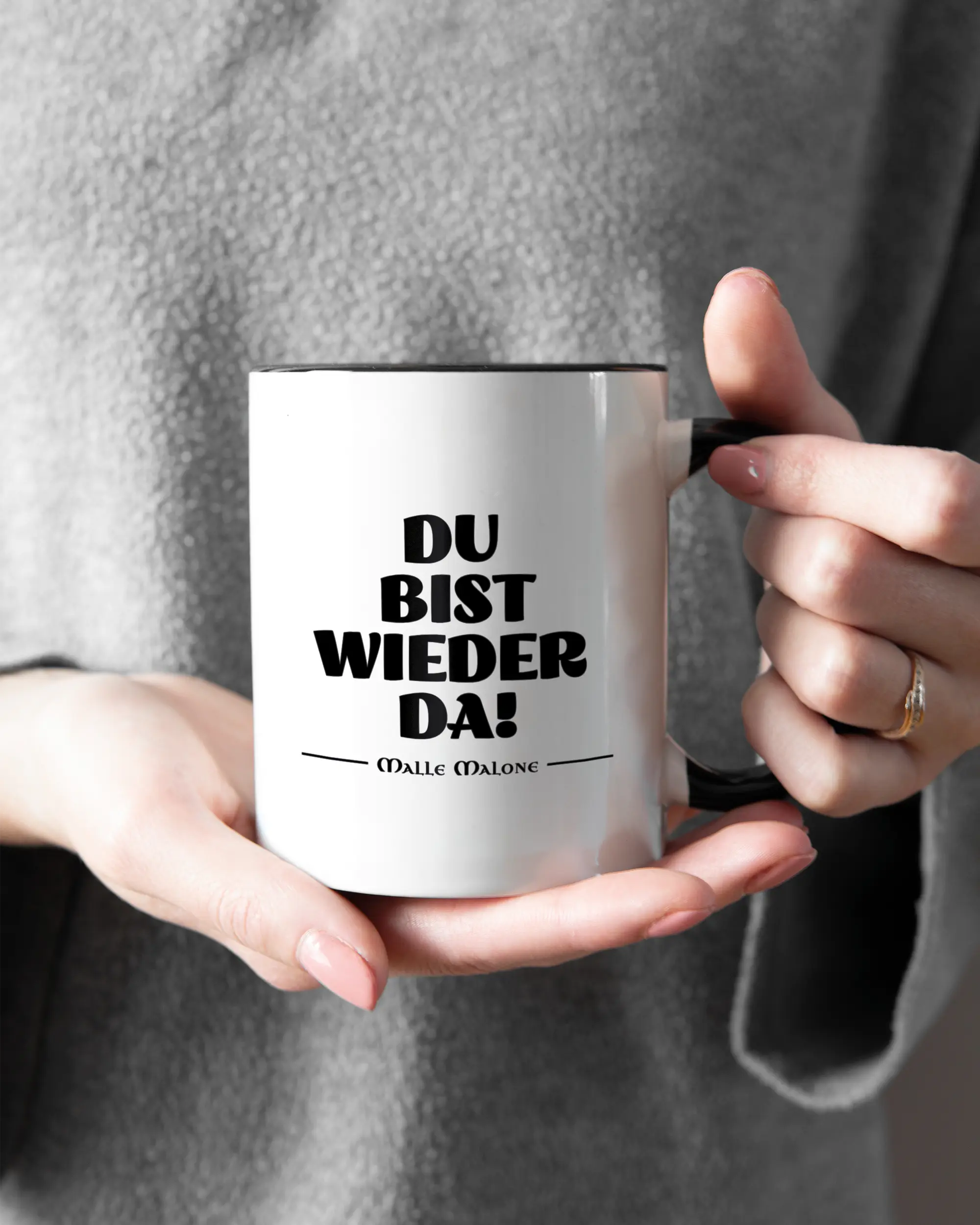 Rechte Seite der beidseitig bedruckten Keramiktasse von Maondo mit dem Design Wieder da in der Farbe Duotone gehalten von Frauenhänden