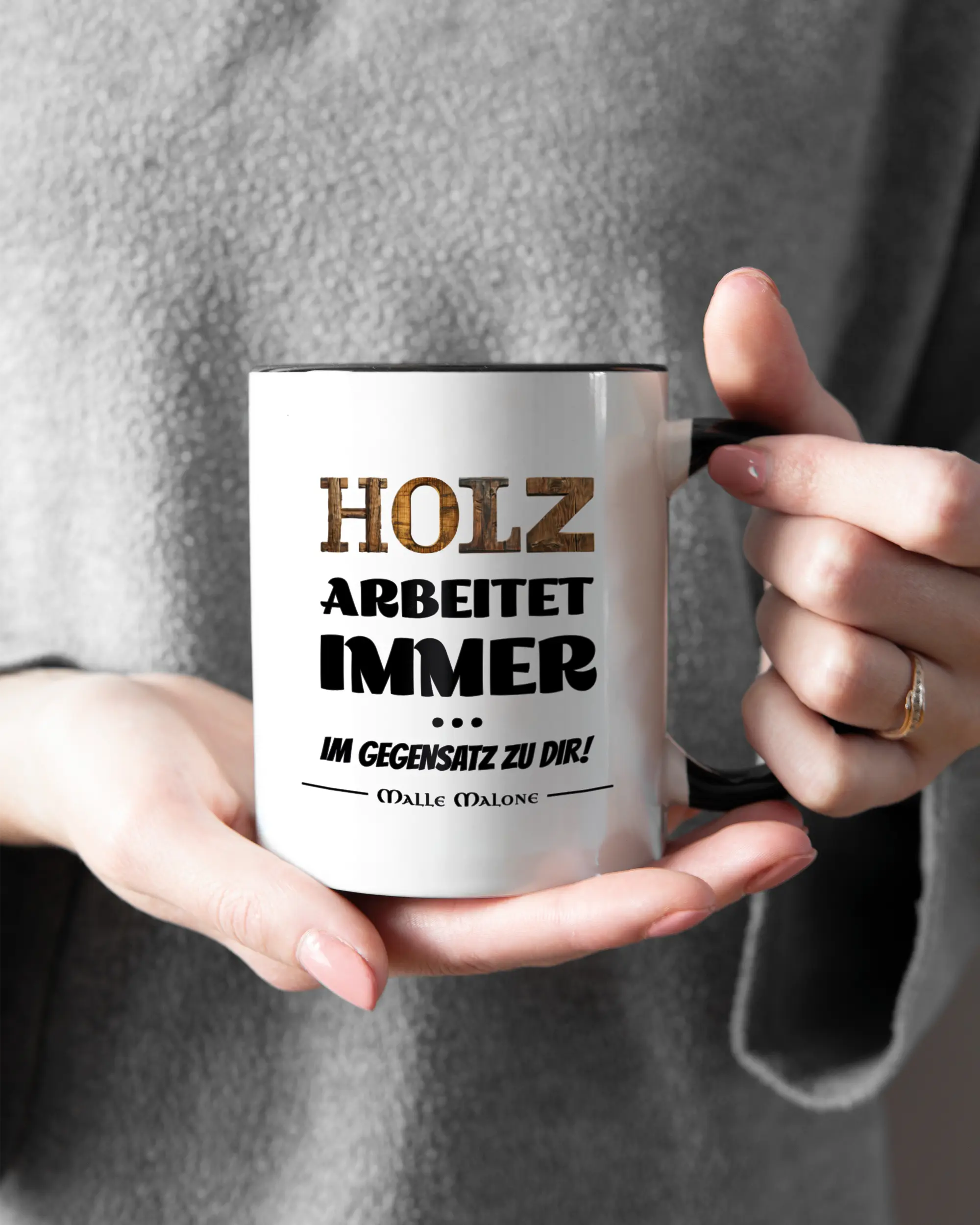 Rechte Seite der beidseitig bedruckten Keramiktasse von Maondo mit dem Design Holzarbeit in der Farbe Duotone gehalten von Frauenhänden