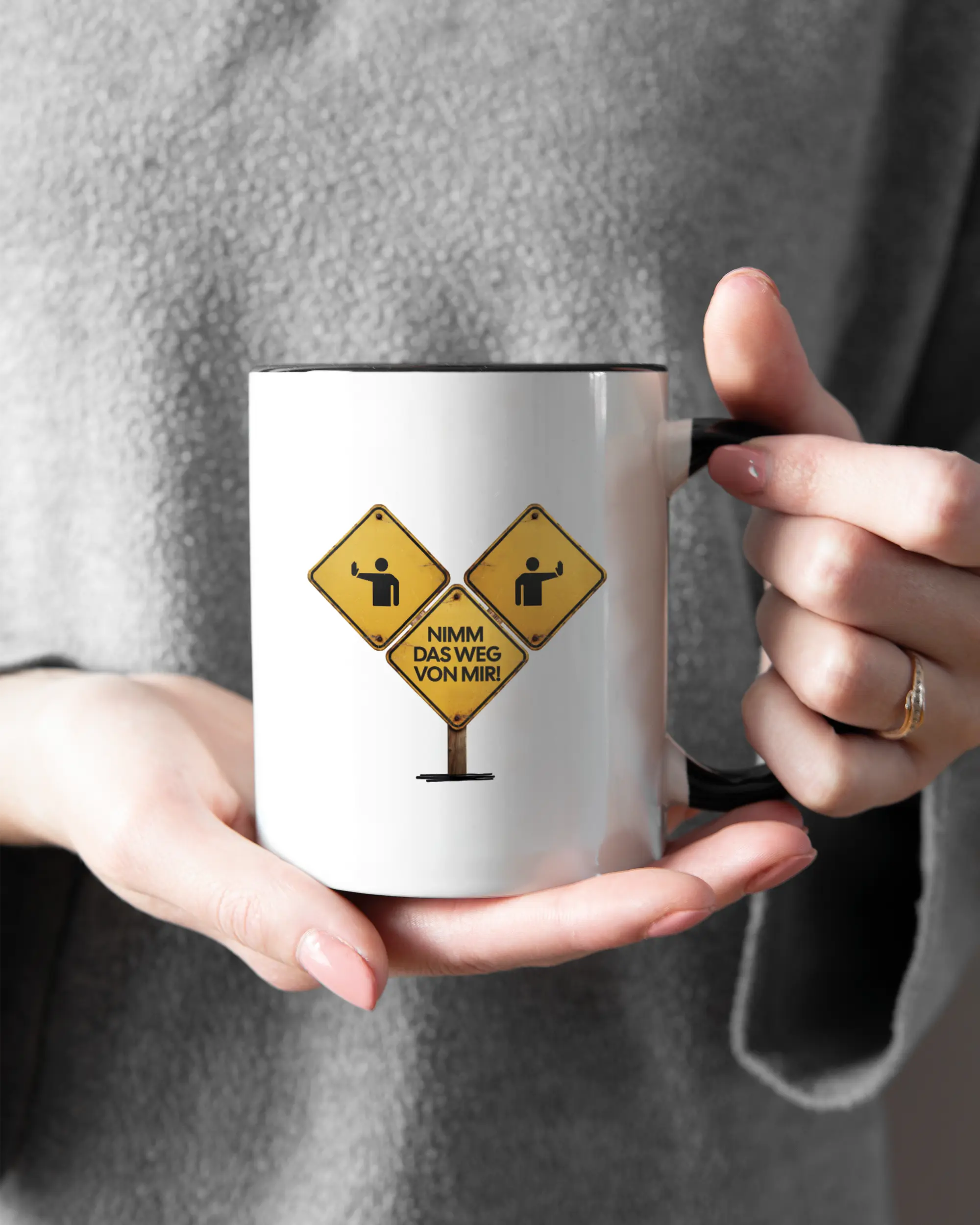 Rechte Seite der beidseitig bedruckten Keramiktasse von Maondo mit dem Design Schutzschild in der Farbe Duotone gehalten von Frauenhänden