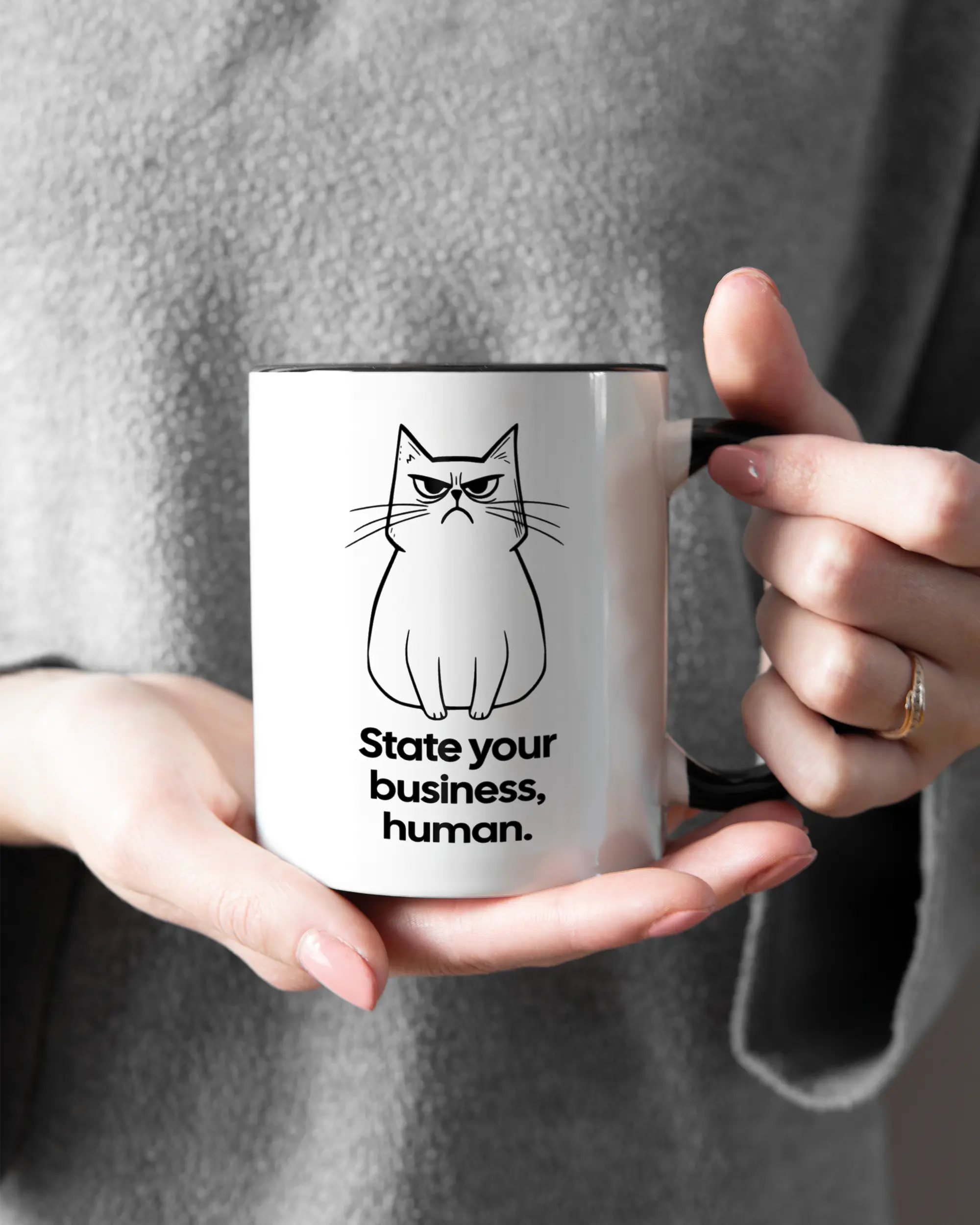 Rechte Seite der beidseitig bedruckten Keramiktasse von Maondo mit dem Design Grumpy Purr in der Farbe Duotone gehalten von Frauenhänden