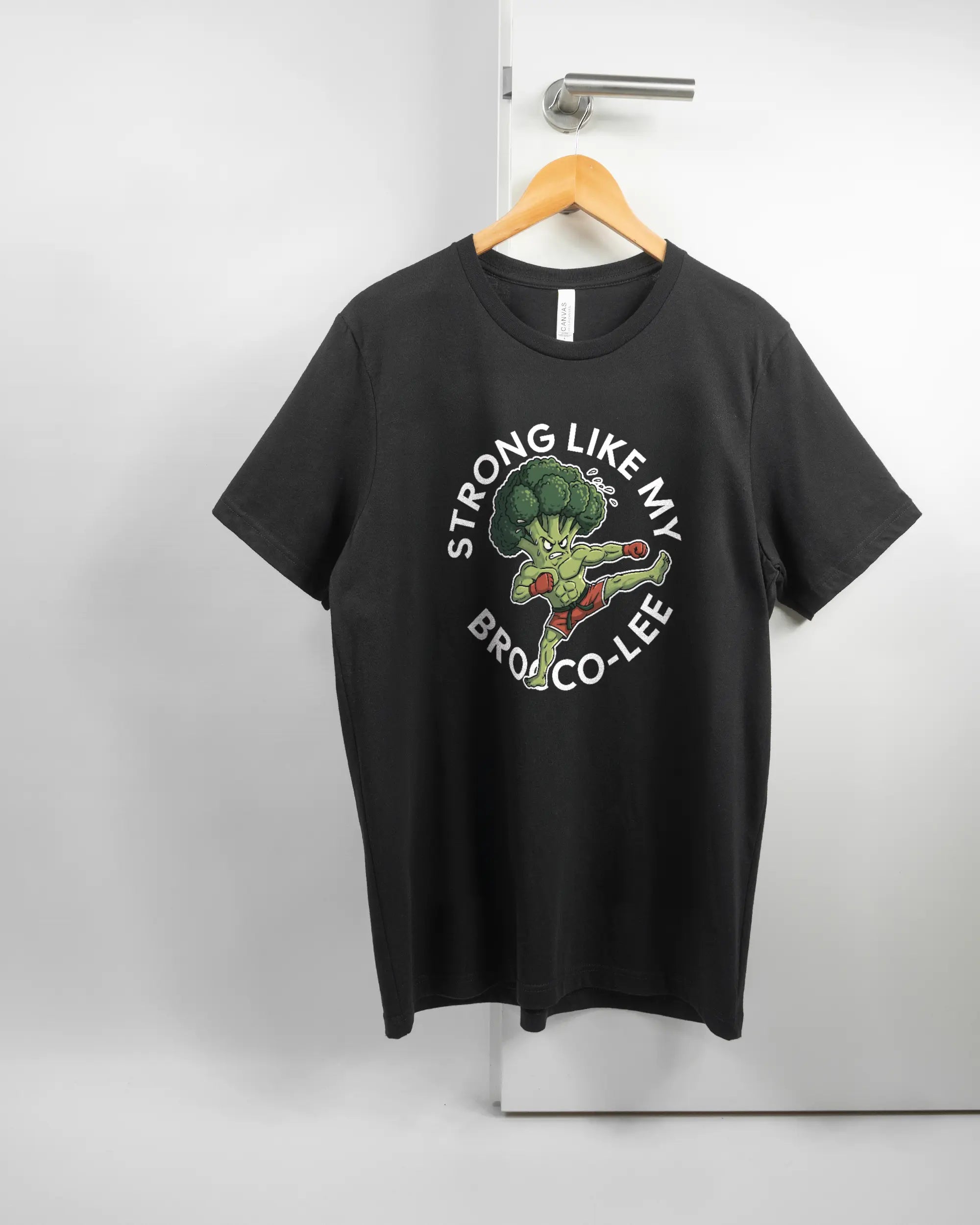 Vorderseite des Basic Unisex T-Shirt Light von Maondo mit dem Design Brocco-Lee in der Farbe Black und in der Größe L auf einem Bügel an der Türklinke aufgehängt