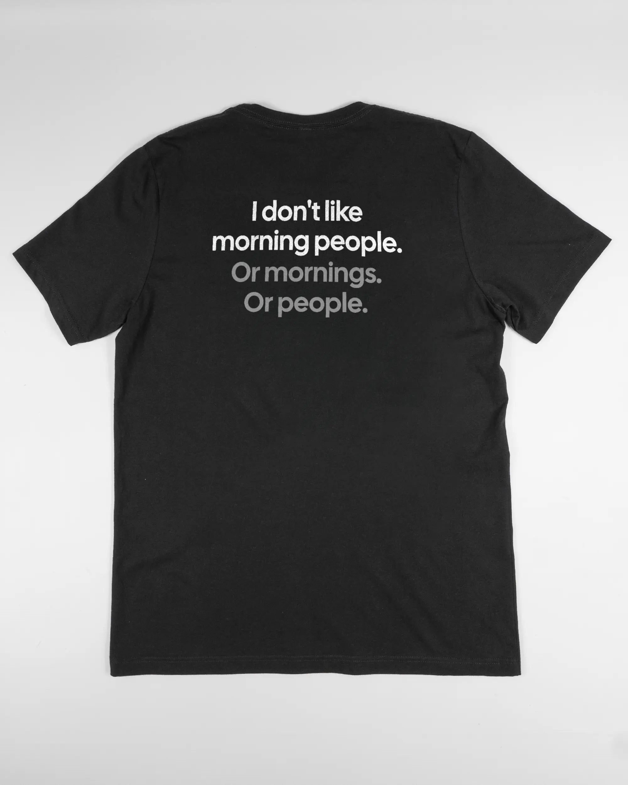 Rückseite des Basic Unisex T-Shirt Light von Maondo mit dem Design Morning Person in der Farbe Black und in der Größe L flach auf den Boden gelegt