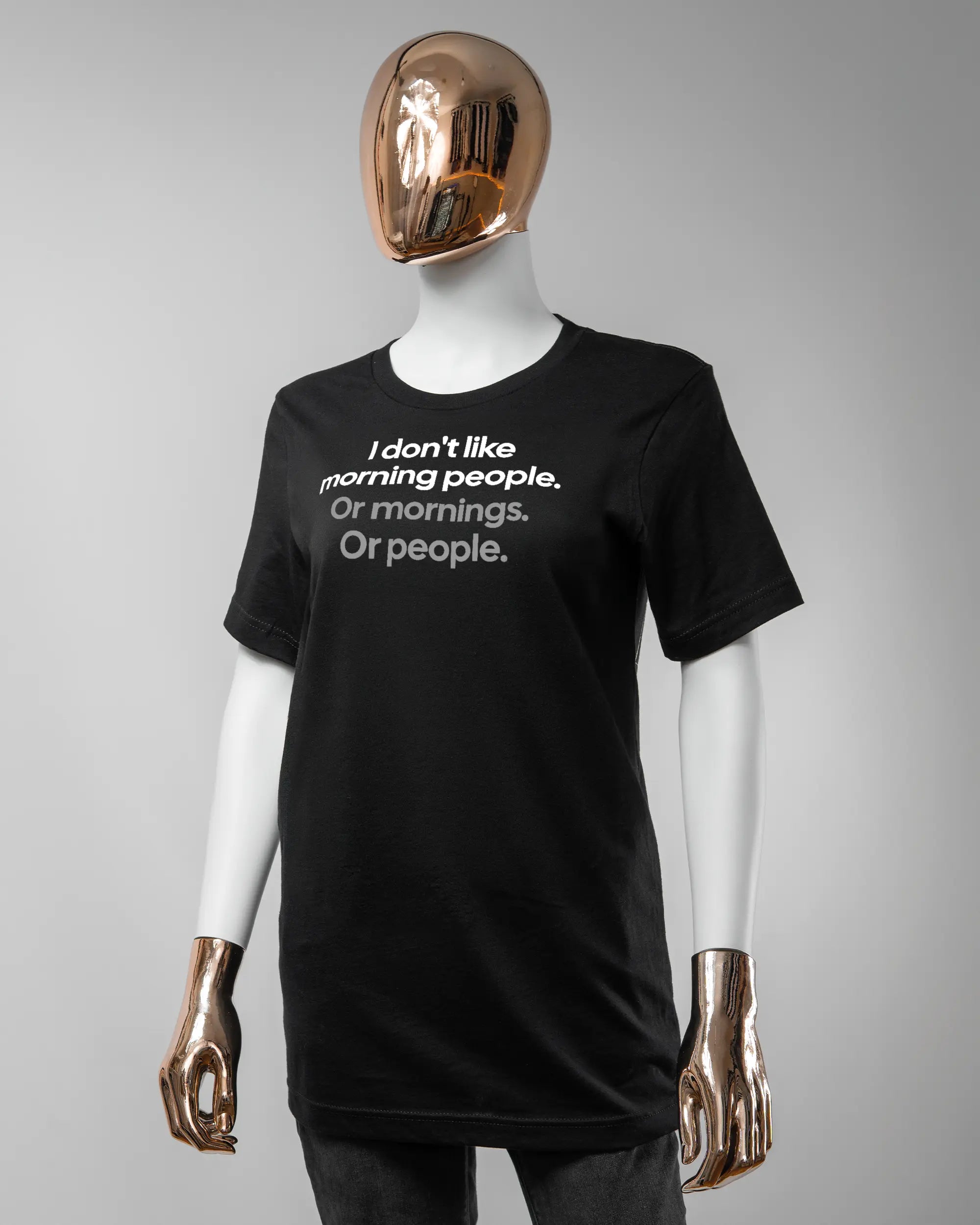 Vorderseite des Basic Unisex T-Shirt Light von Maondo mit dem Design Morning Person in der Farbe Black und in der Größe S getragen von einer femininen Puppe