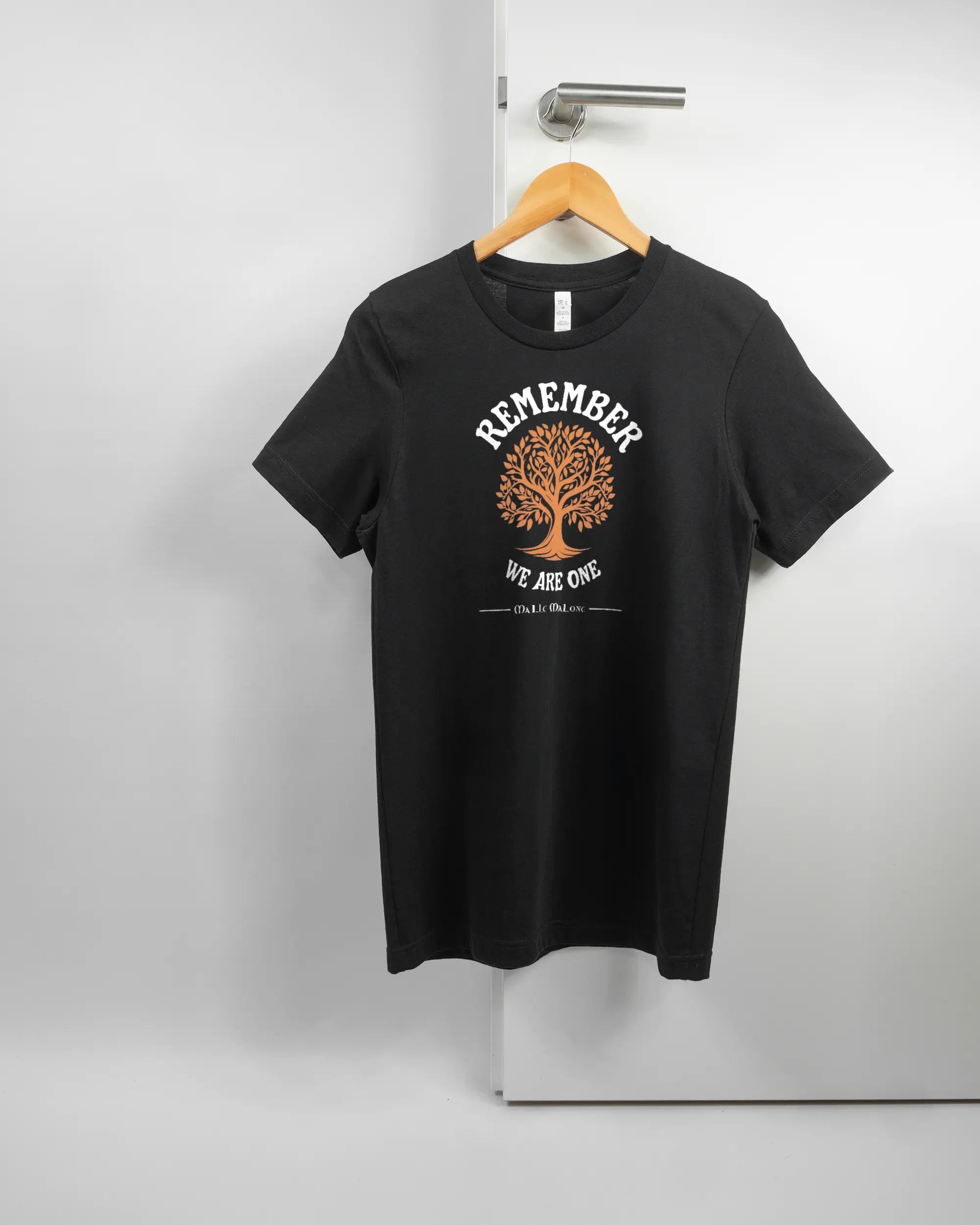 Vorderseite des Basic Unisex T-Shirt Light von Maondo mit dem Design We are one in der Farbe Black und in der Größe S auf einem Bügel an der Türklinke aufgehängt
