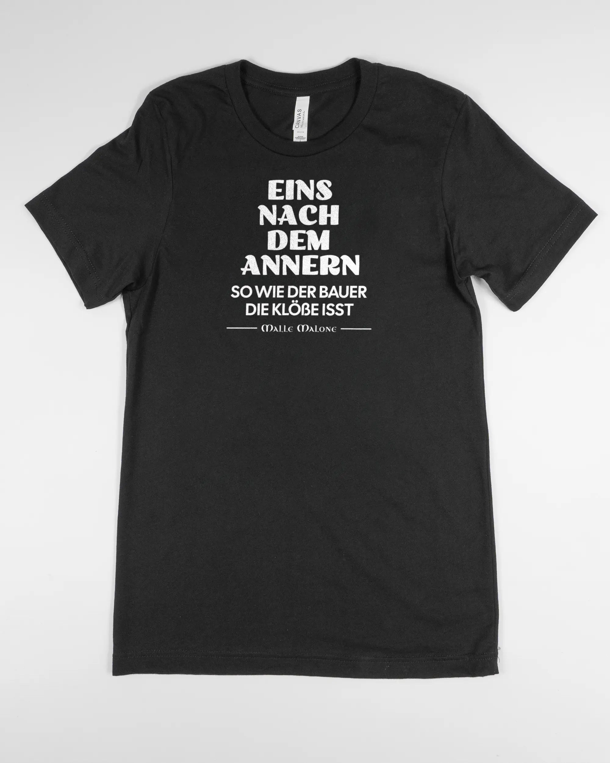 Vorderseite des Basic Unisex T-Shirt Light von Maondo mit dem Design Eins nach dem Annern in der Farbe Black und in der Größe S flach auf den Boden gelegt