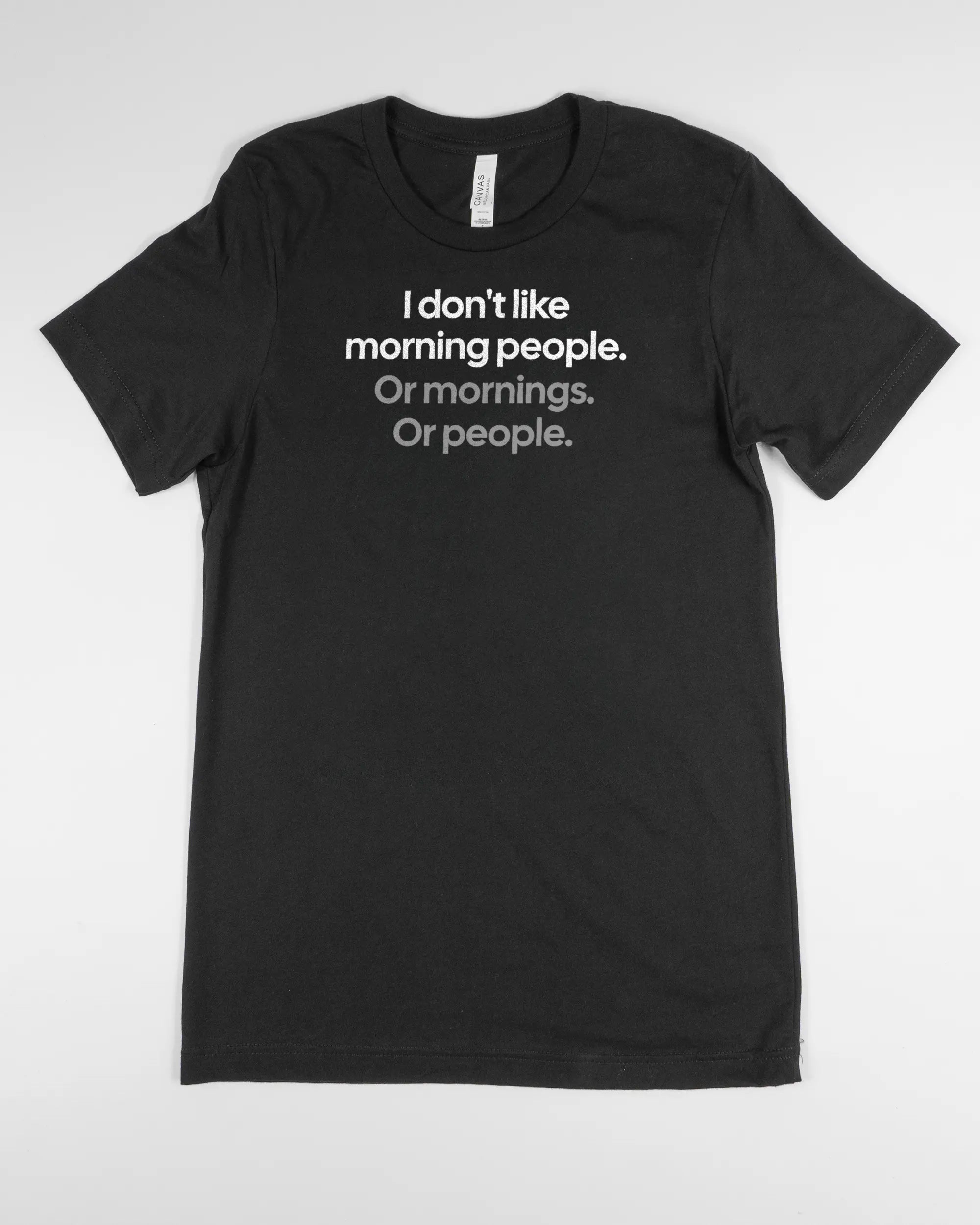 Vorderseite des Basic Unisex T-Shirt Light von Maondo mit dem Design Morning Person in der Farbe Black und in der Größe S flach auf den Boden gelegt