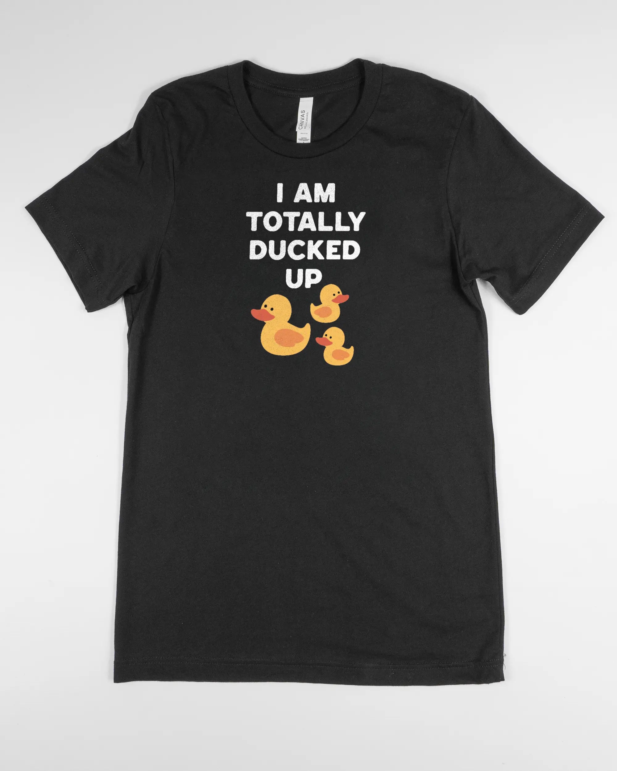 Vorderseite des Basic Unisex T-Shirt Light von Maondo mit dem Design Ducked Up in der Farbe Black und in der Größe S flach auf den Boden gelegt