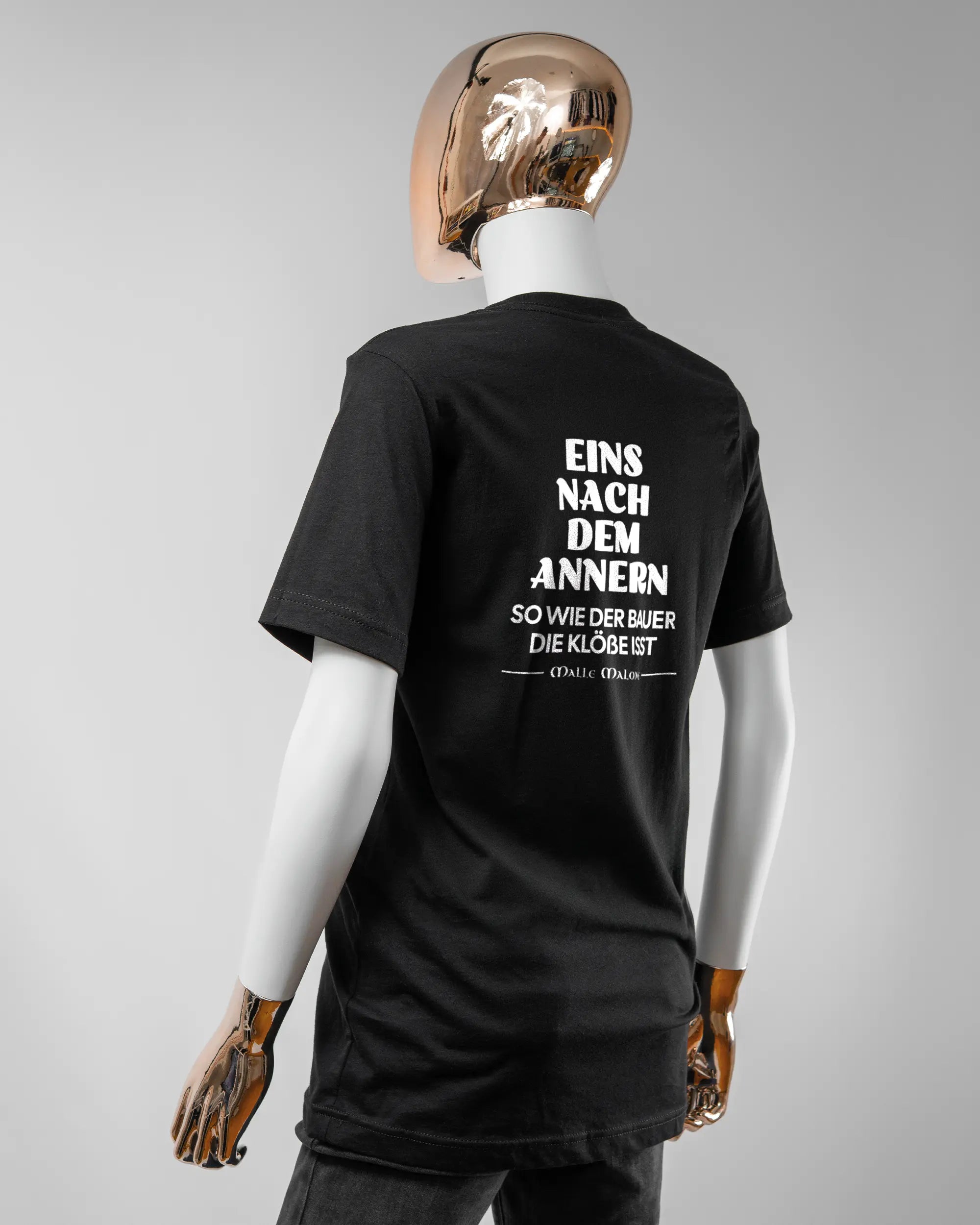 Rückseite des Basic Unisex T-Shirt Light von Maondo mit dem Design Eins nach dem Annern in der Farbe Black und in der Größe S getragen von einer femininen Puppe