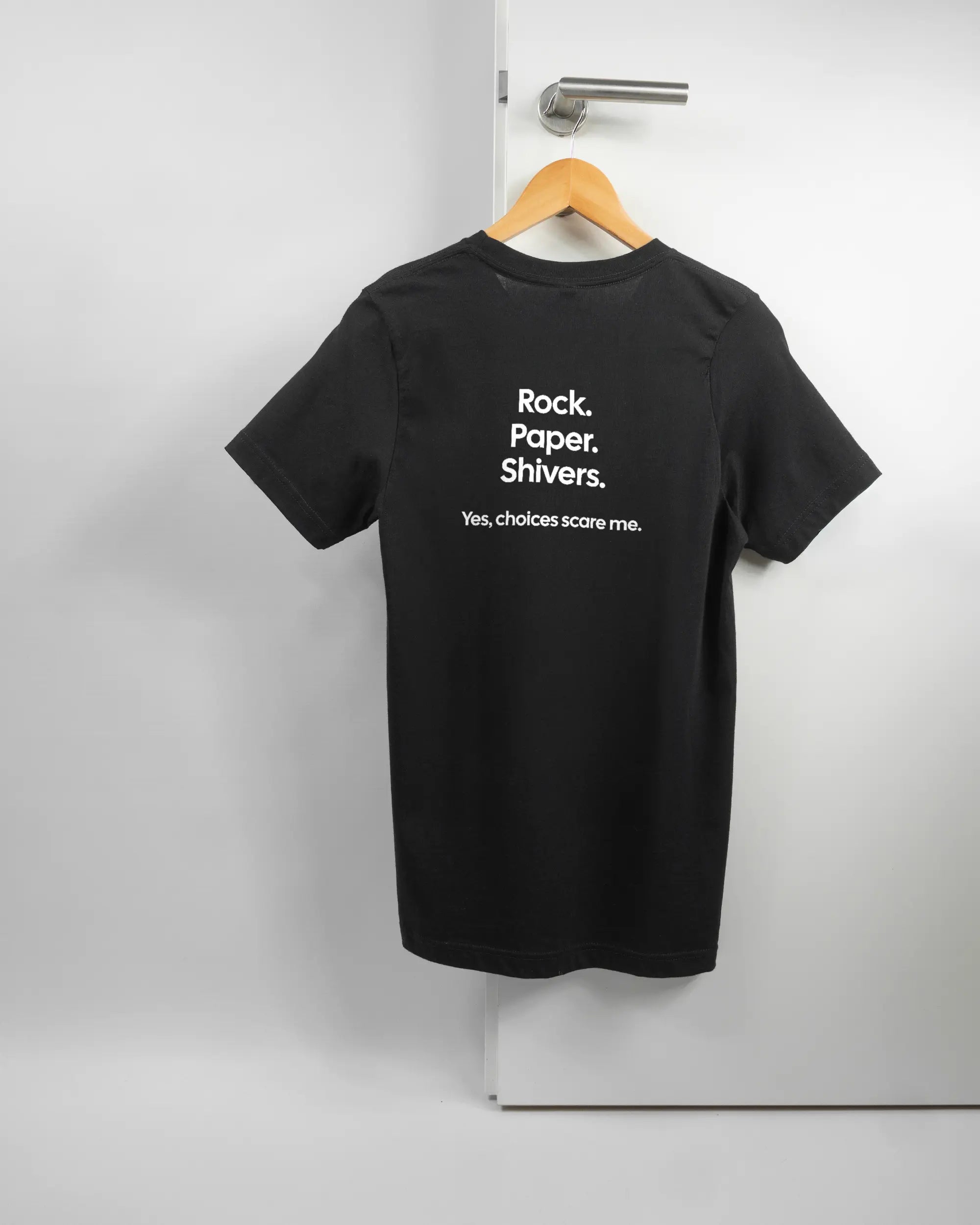 Rückseite des Basic Unisex T-Shirt Light von Maondo mit dem Design Rock Paper Shivers in der Farbe Black und in der Größe S auf einem Bügel an der Türklinke aufgehängt