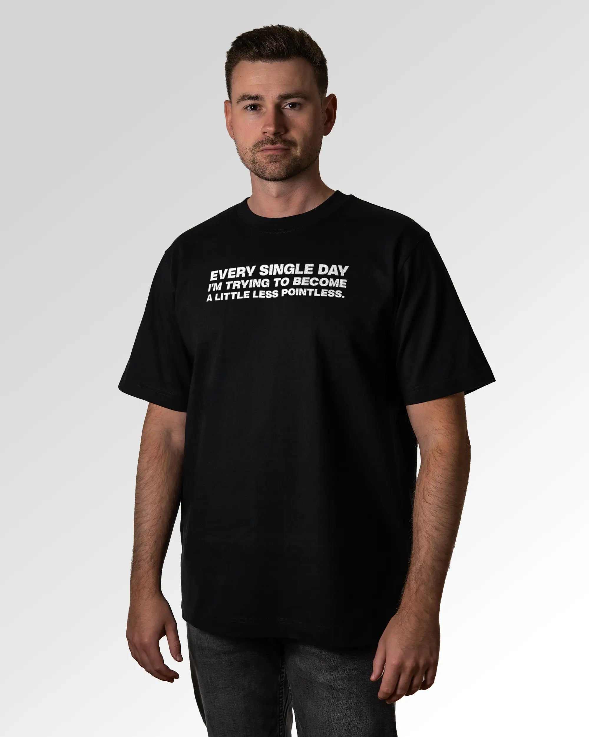 Primärer Modelshot der Druckseite des Organic Unisex T-Shirts von Maondo im Oversized Fit mit dem Design Less Pointless in der Farbe Black