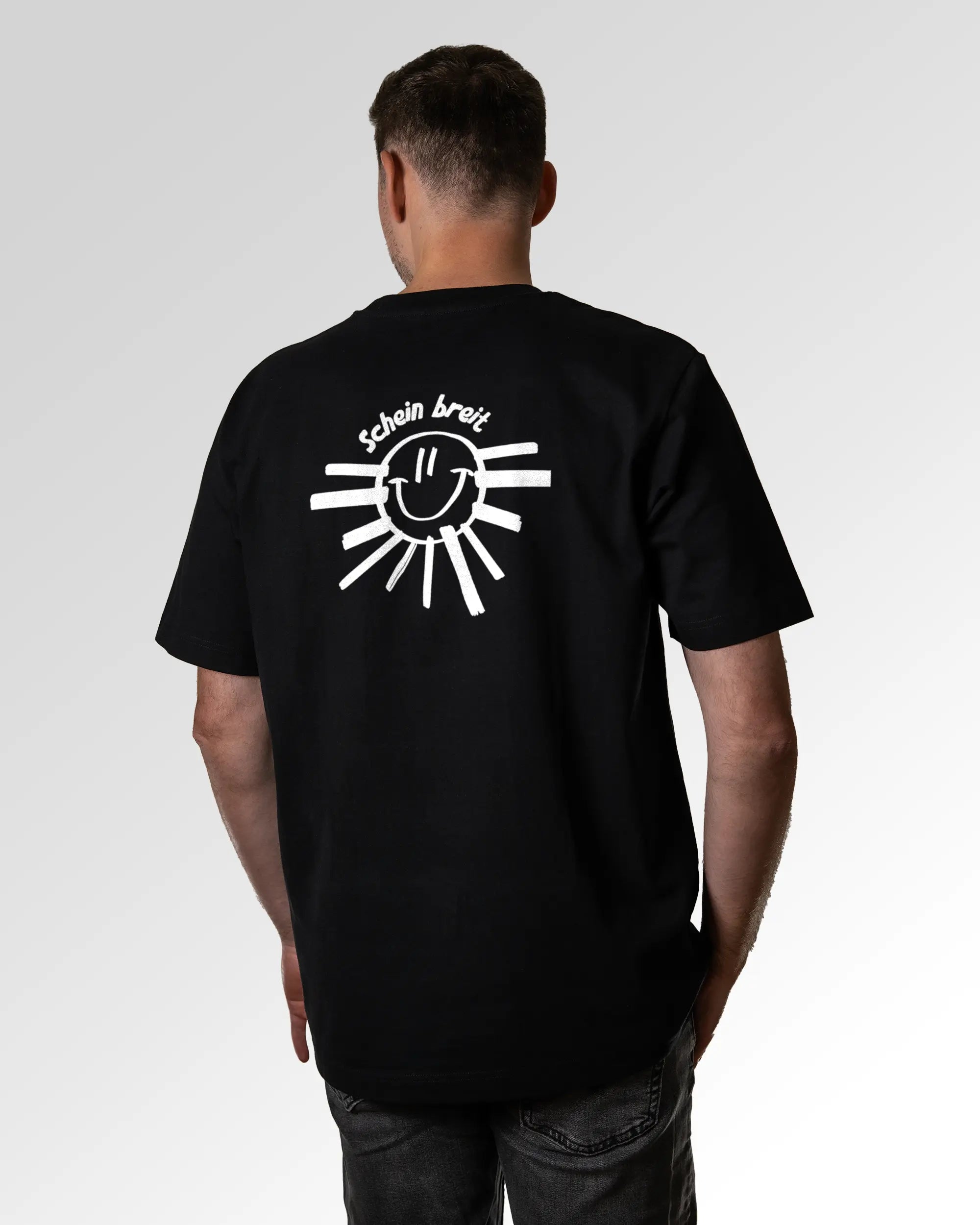 Primärer Modelshot der Druckseite des Organic Unisex T-Shirts von Maondo im Oversized Fit mit dem Design Schein Breit in der Farbe Black