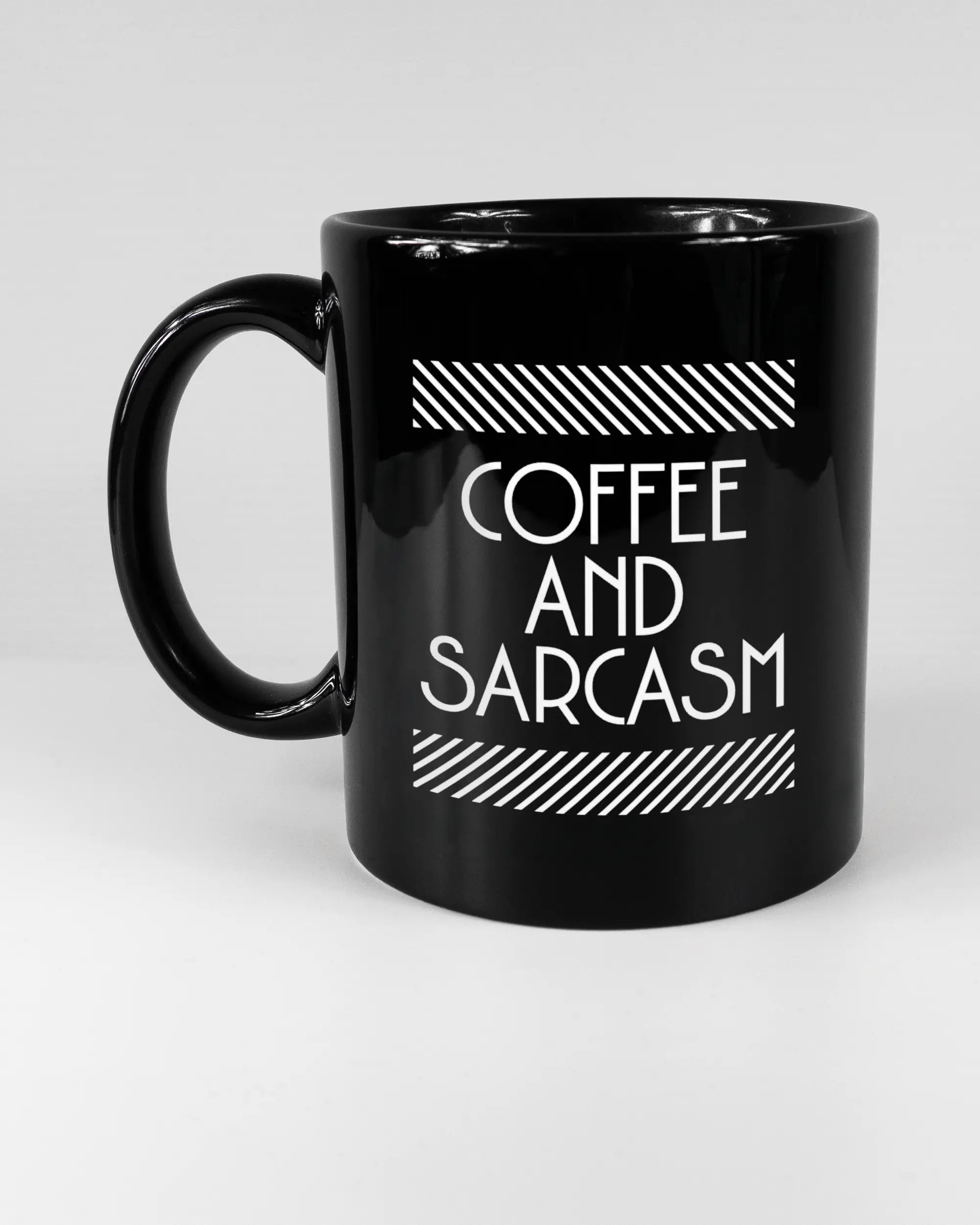 Titelbild, das die linke Seite der beidseitig bedruckten Keramiktasse von Maondo mit dem Design Sarcastic Cup in der Farbe Black auf einem Holztisch zeigt