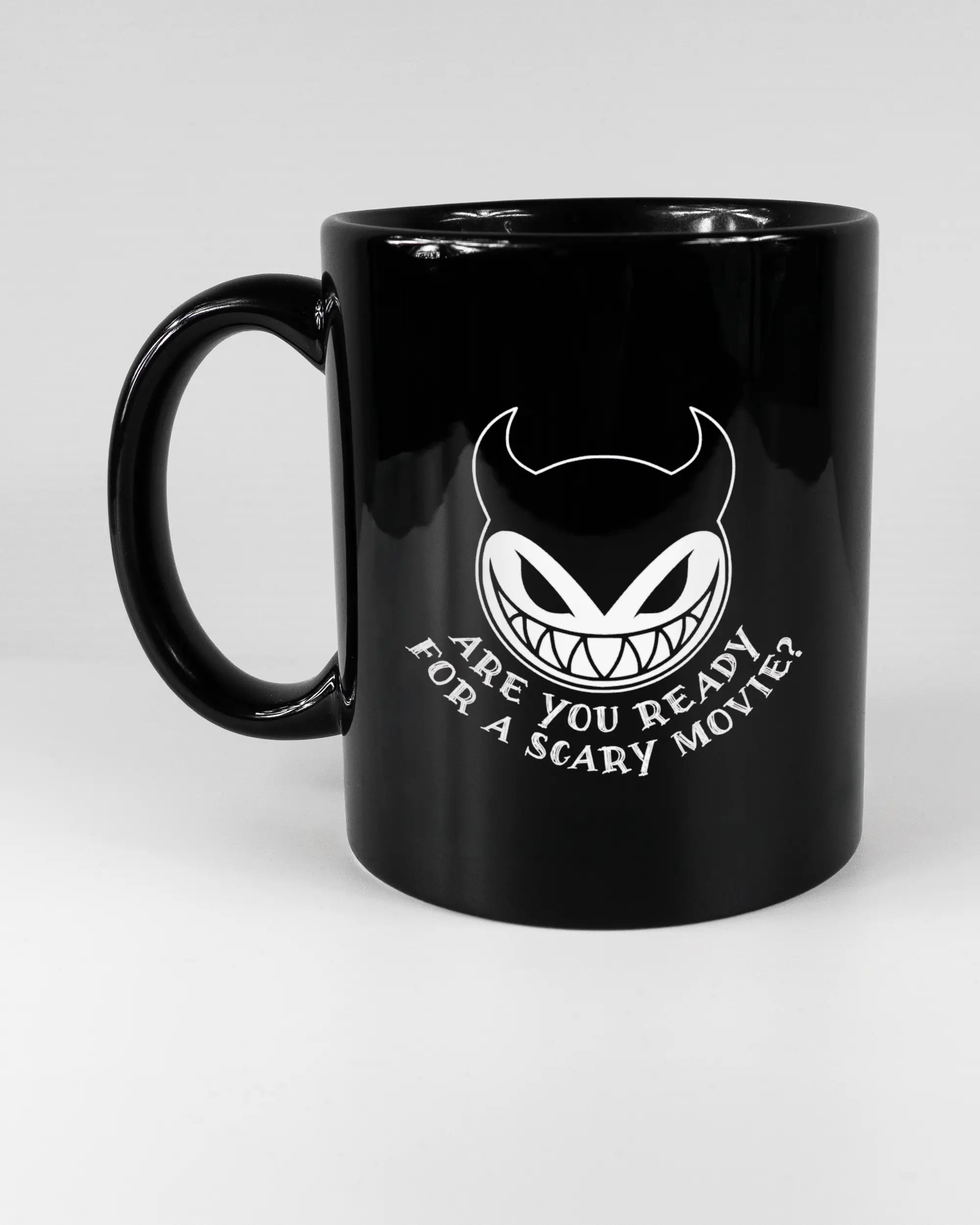 Titelbild, das die linke Seite der beidseitig bedruckten Keramiktasse von Maondo mit dem Design Scary Movie in der Farbe Black auf einem Holztisch zeigt