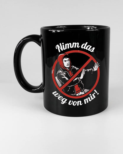 Titelbild, das die linke Seite der beidseitig bedruckten Keramiktasse von Maondo mit dem Design Nimm das weg in der Farbe Black auf einem Holztisch zeigt