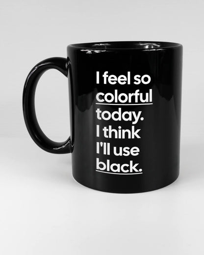 Titelbild, das die linke Seite der beidseitig bedruckten Keramiktasse von Maondo mit dem Design Colorful Day in der Farbe Black auf einem Holztisch zeigt