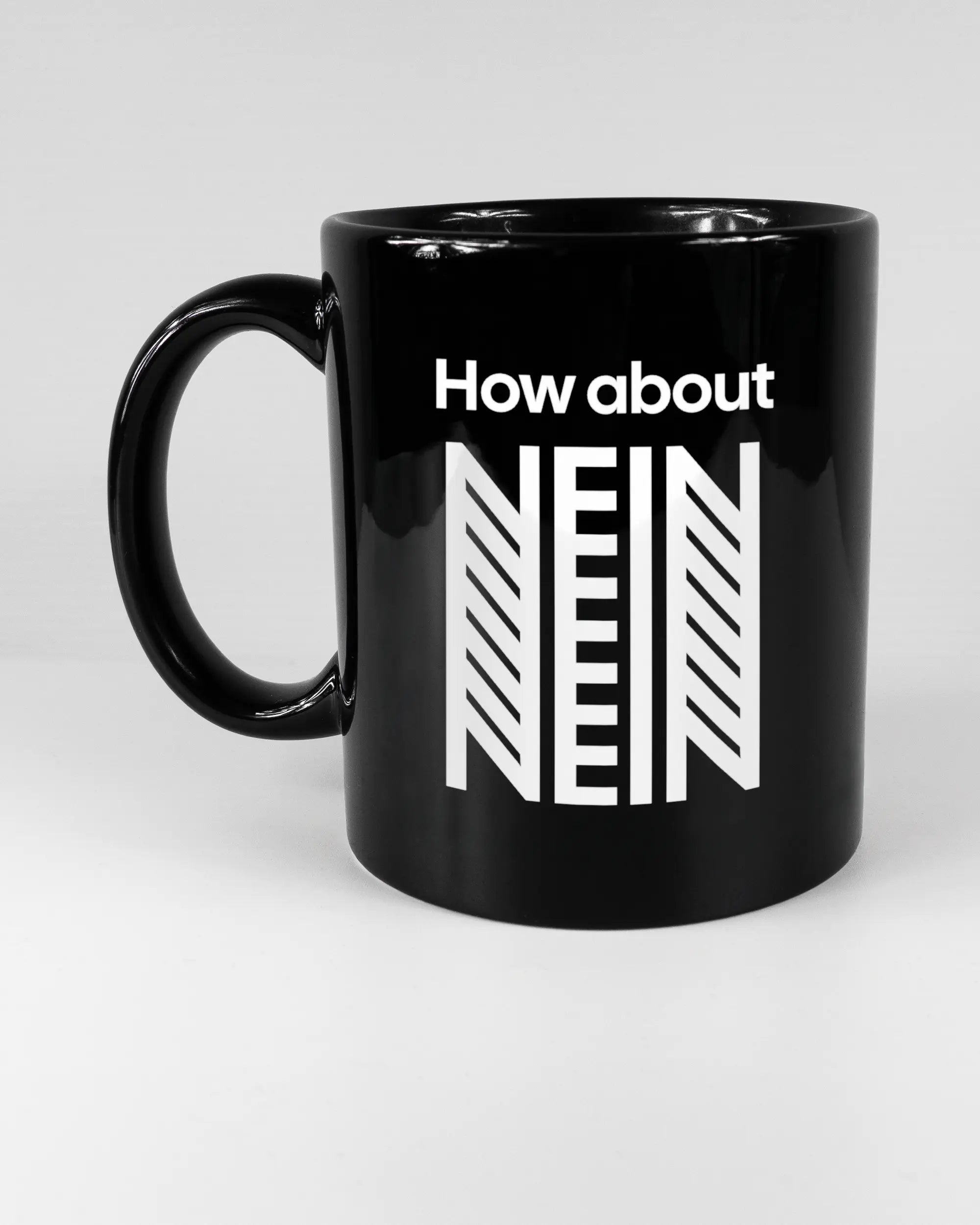 Titelbild, das die linke Seite der beidseitig bedruckten Keramiktasse von Maondo mit dem Design How about nein in der Farbe Black auf einem Holztisch zeigt