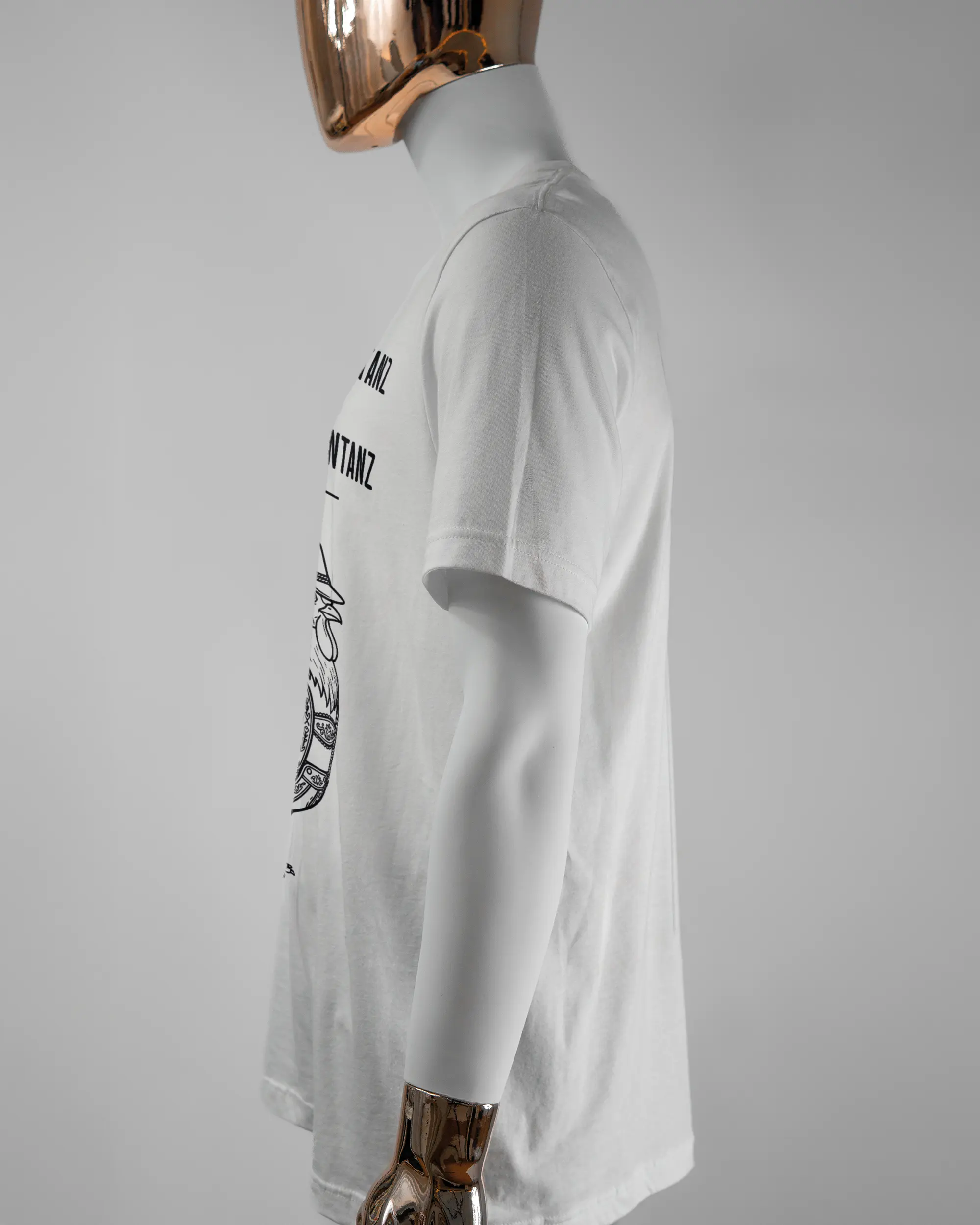 Seitenansicht des Basic Unisex T-Shirt Light von Maondo mit dem Design Trachtentanz vorne in der Farbe White und in der Größe L getragen von einer maskulinen Puppe
