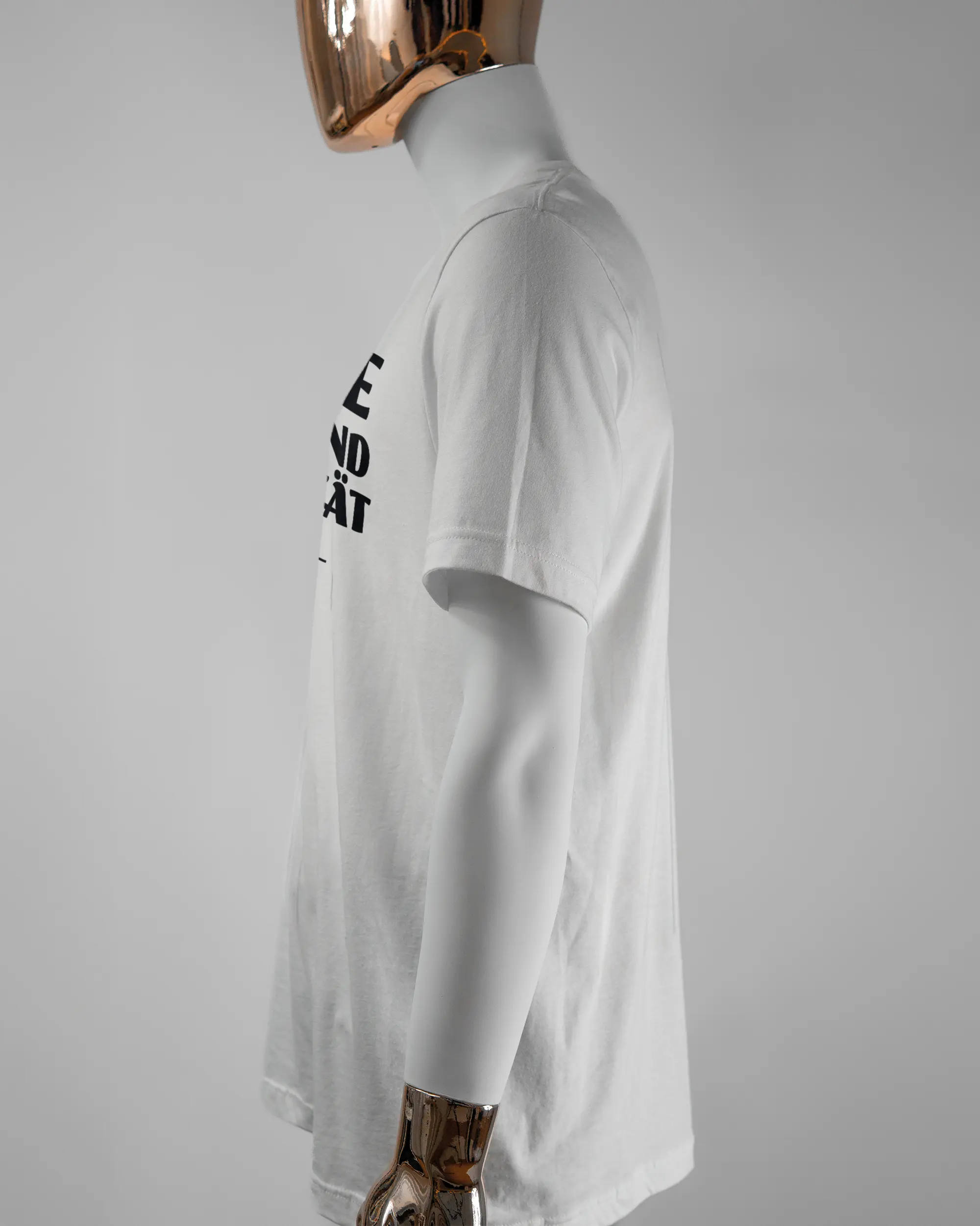 Seitenansicht des Basic Unisex T-Shirt Light von Maondo mit dem Design Keine Eile vorne in der Farbe White und in der Größe L getragen von einer maskulinen Puppe