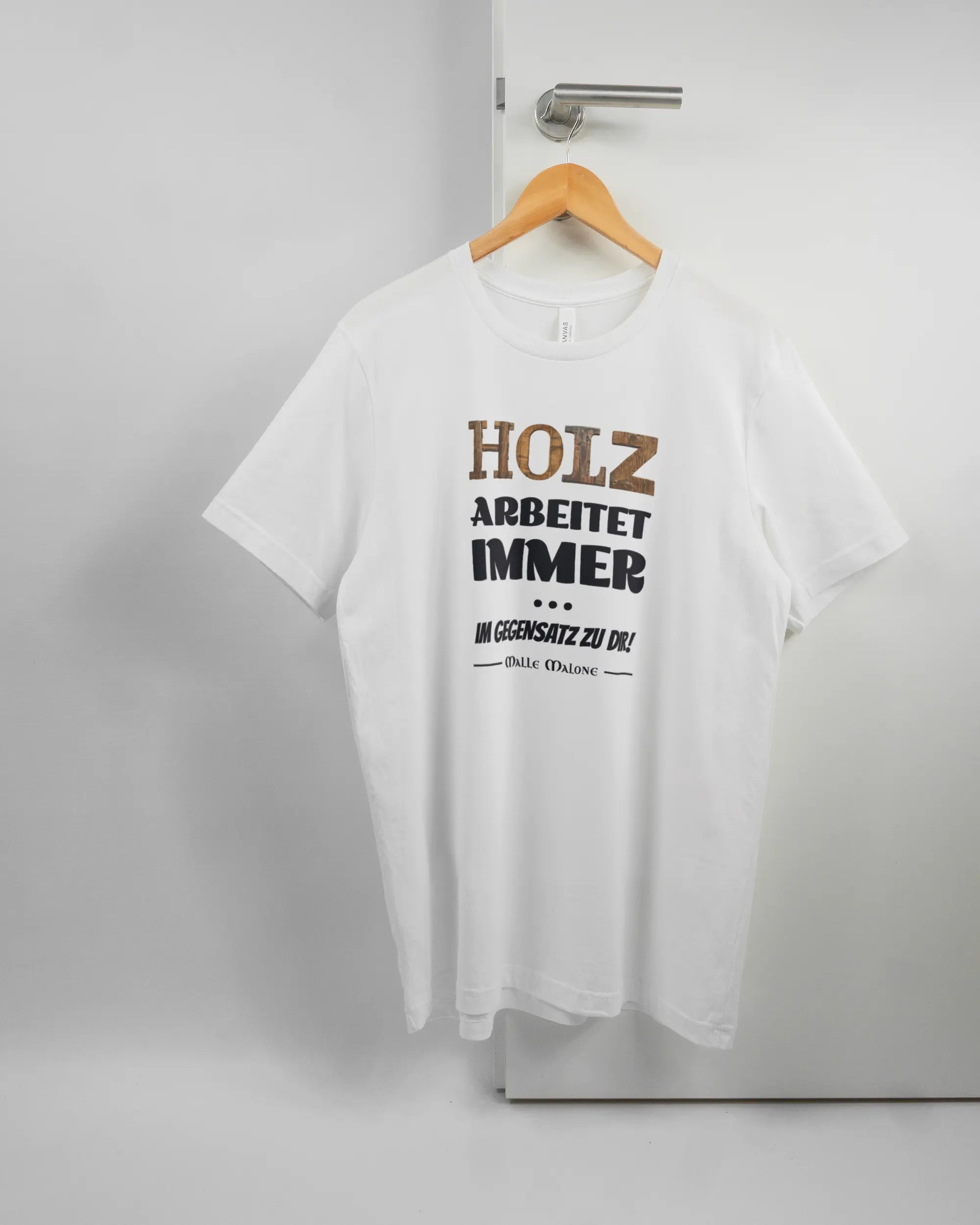 Vorderseite des Basic Unisex T-Shirt Light von Maondo mit dem Design Holzarbeit in der Farbe White und in der Größe L auf einem Bügel an der Türklinke aufgehängt
