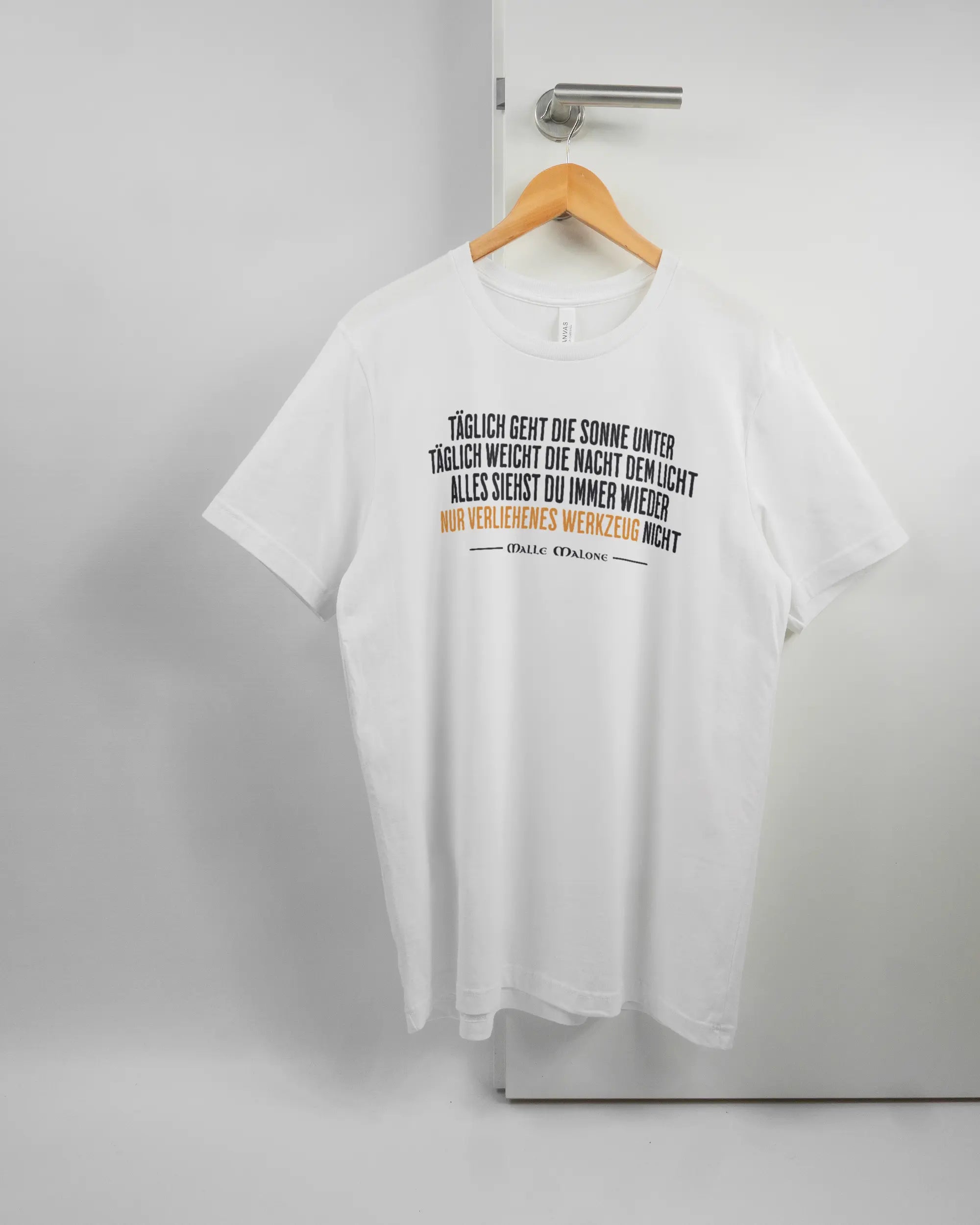 Vorderseite des Basic Unisex T-Shirt Light von Maondo mit dem Design Wegzeug in der Farbe White und in der Größe L auf einem Bügel an der Türklinke aufgehängt