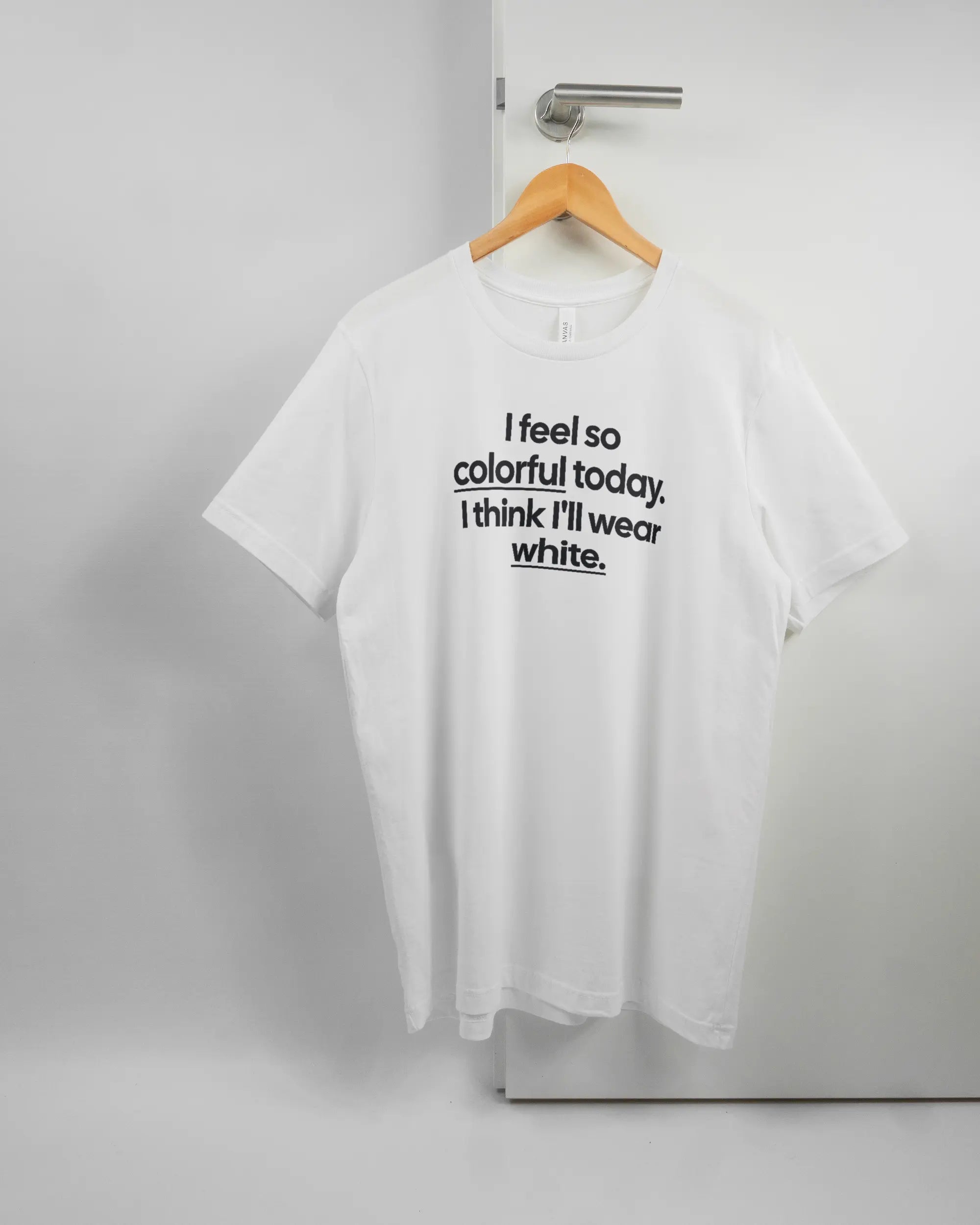 Vorderseite des Basic Unisex T-Shirt Light von Maondo mit dem Design Colorful Day in der Farbe White und in der Größe L auf einem Bügel an der Türklinke aufgehängt